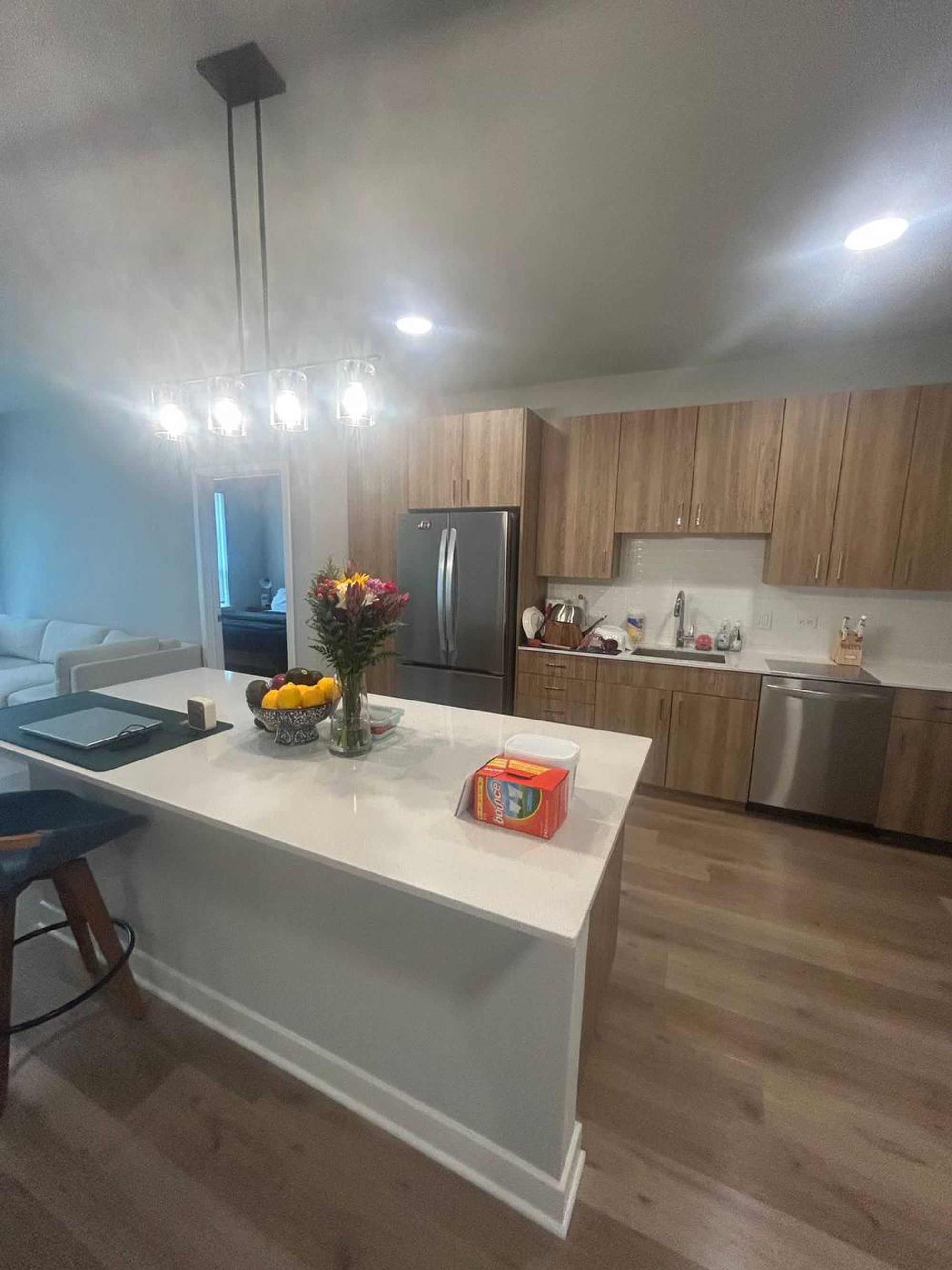 Open kitchen with white island, wood cabinets and steel appliances