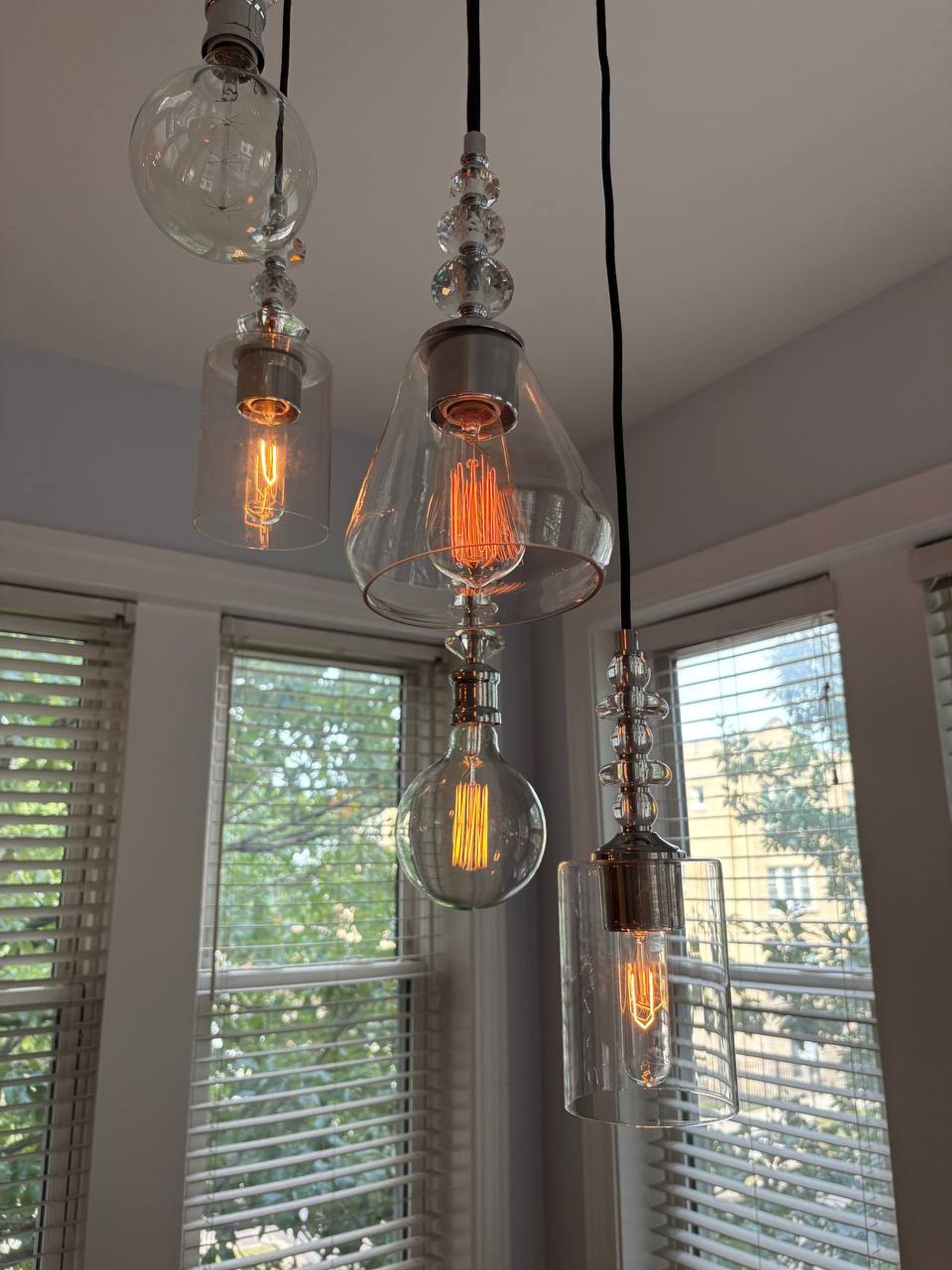 Glass pendant lights over a dining nook with white blinds