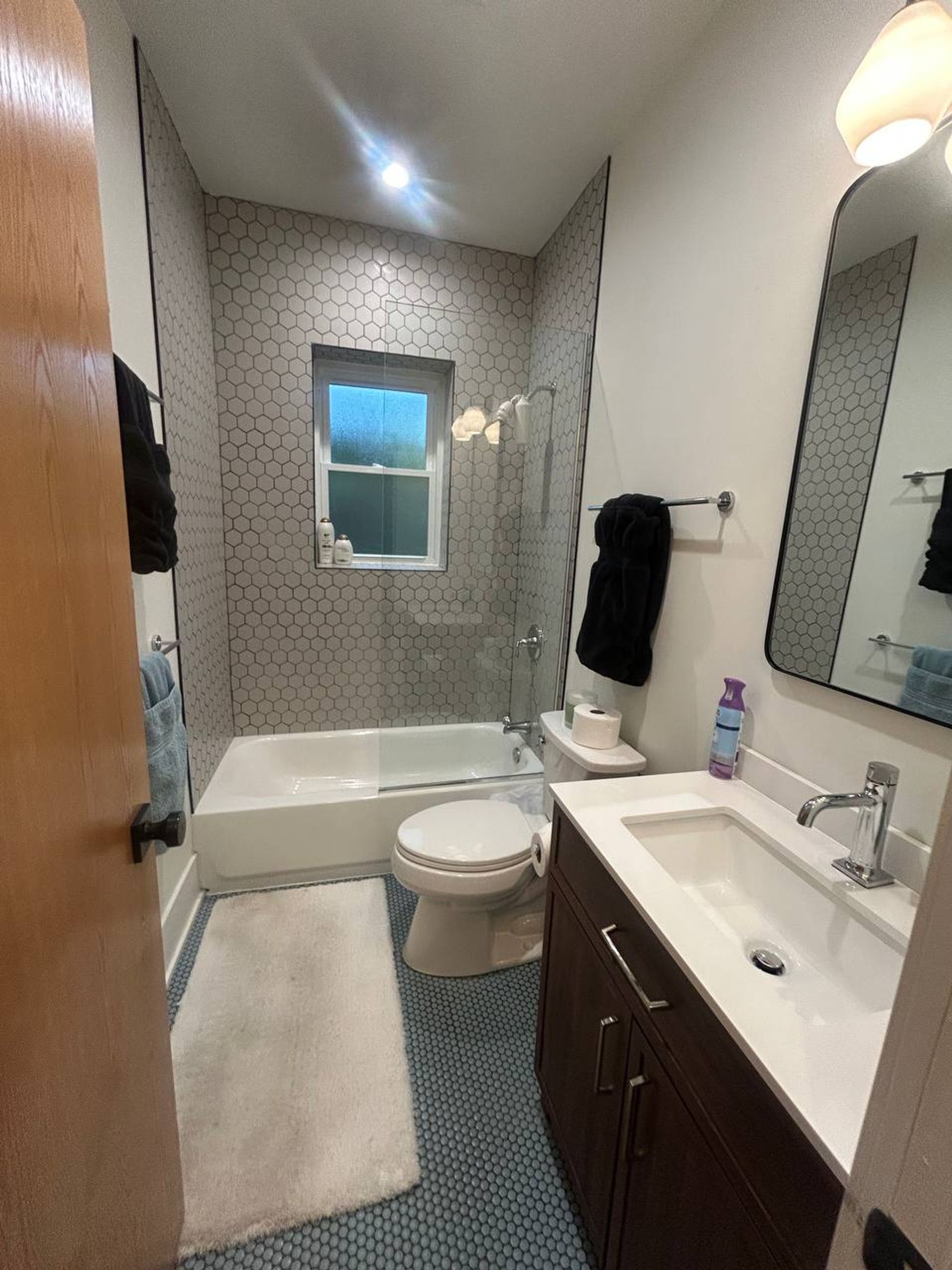 Bathroom with gray hexagon tile tub wall and dark wood vanity