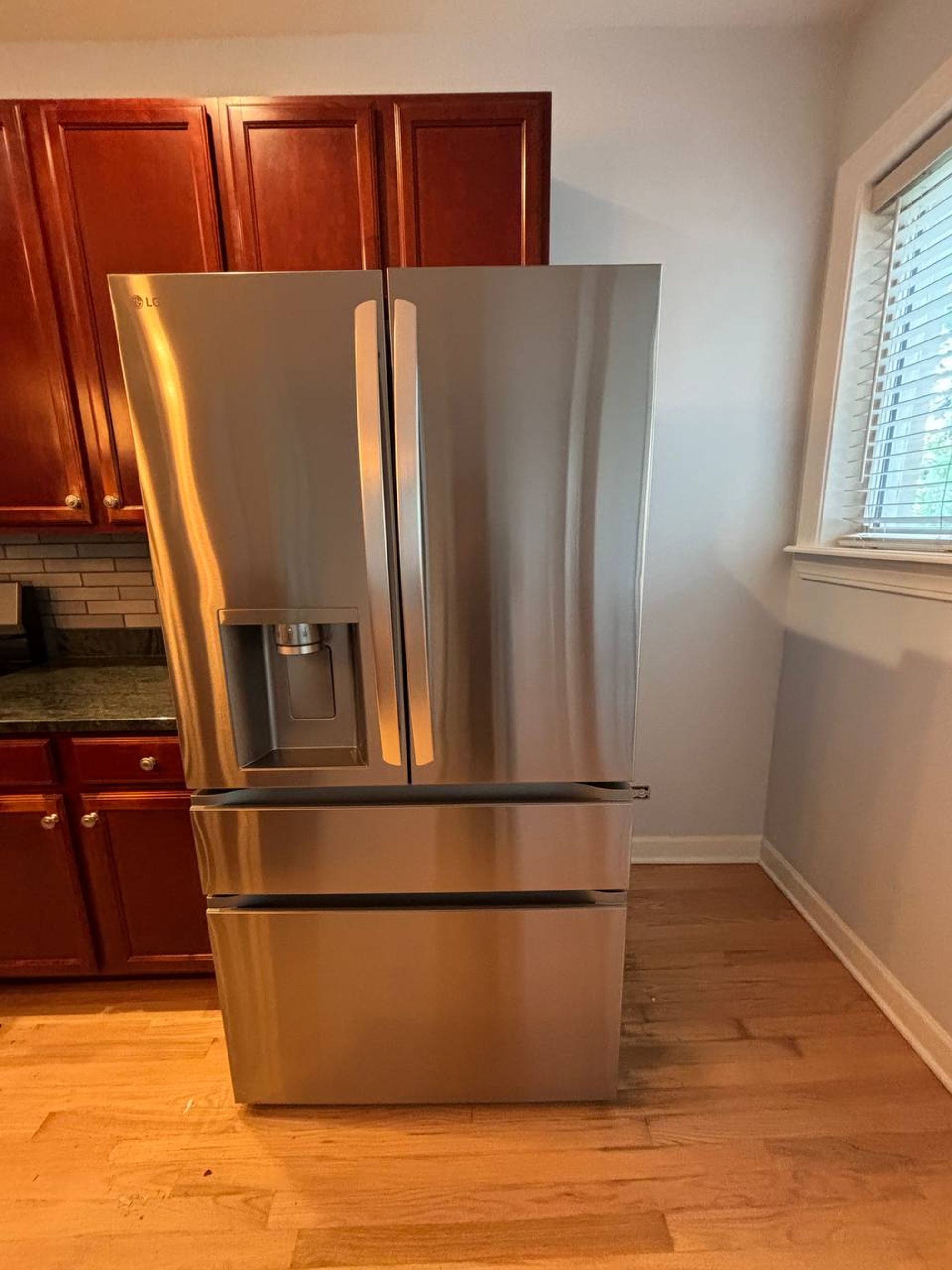 Stainless French door fridge beside cherry kitchen cabinets