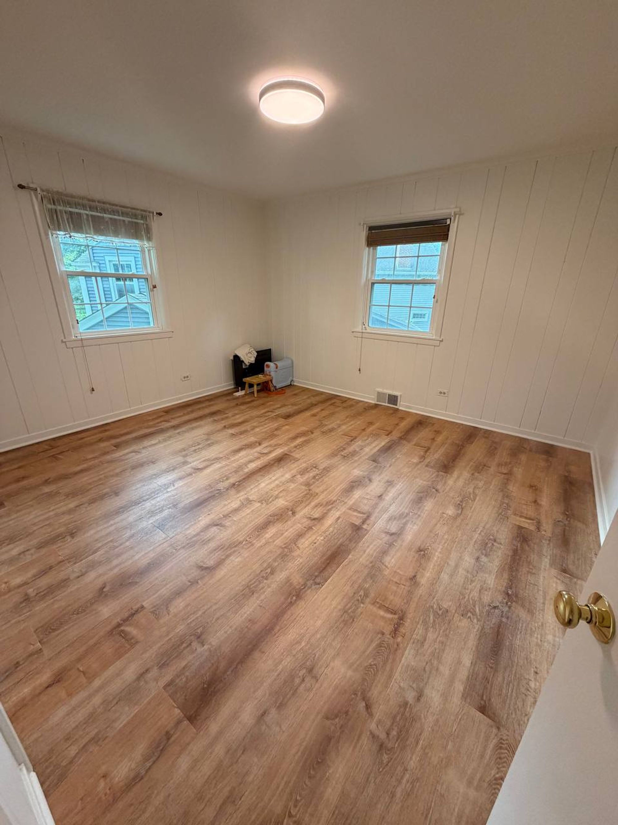 Bedroom with white wood paneling and clean wood-look floors