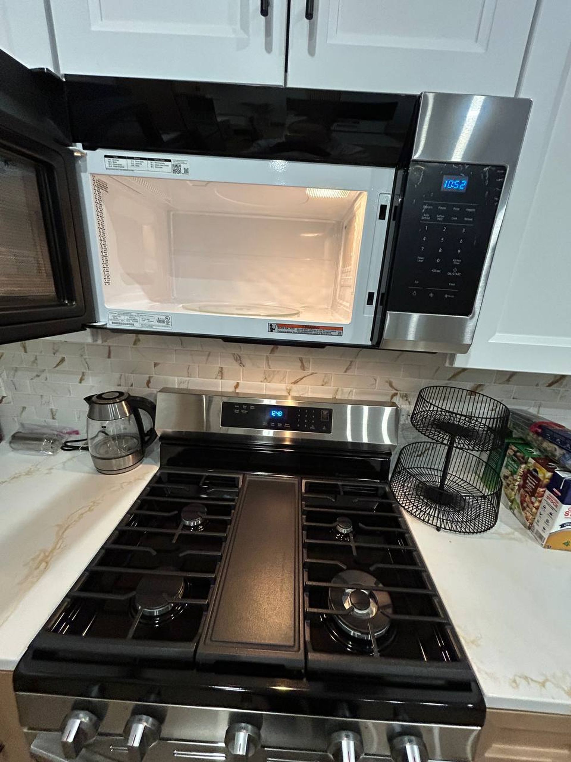 Clean microwave interior above a stainless gas range with griddle