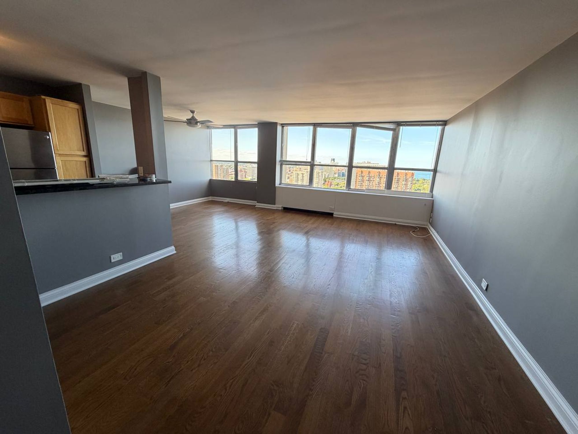 Empty open living area with dark wood floors and wall of windows