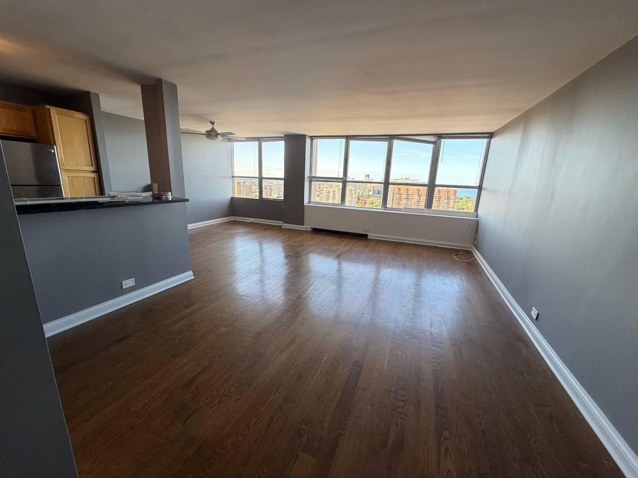 Empty open living area with dark wood floors and wall of windows