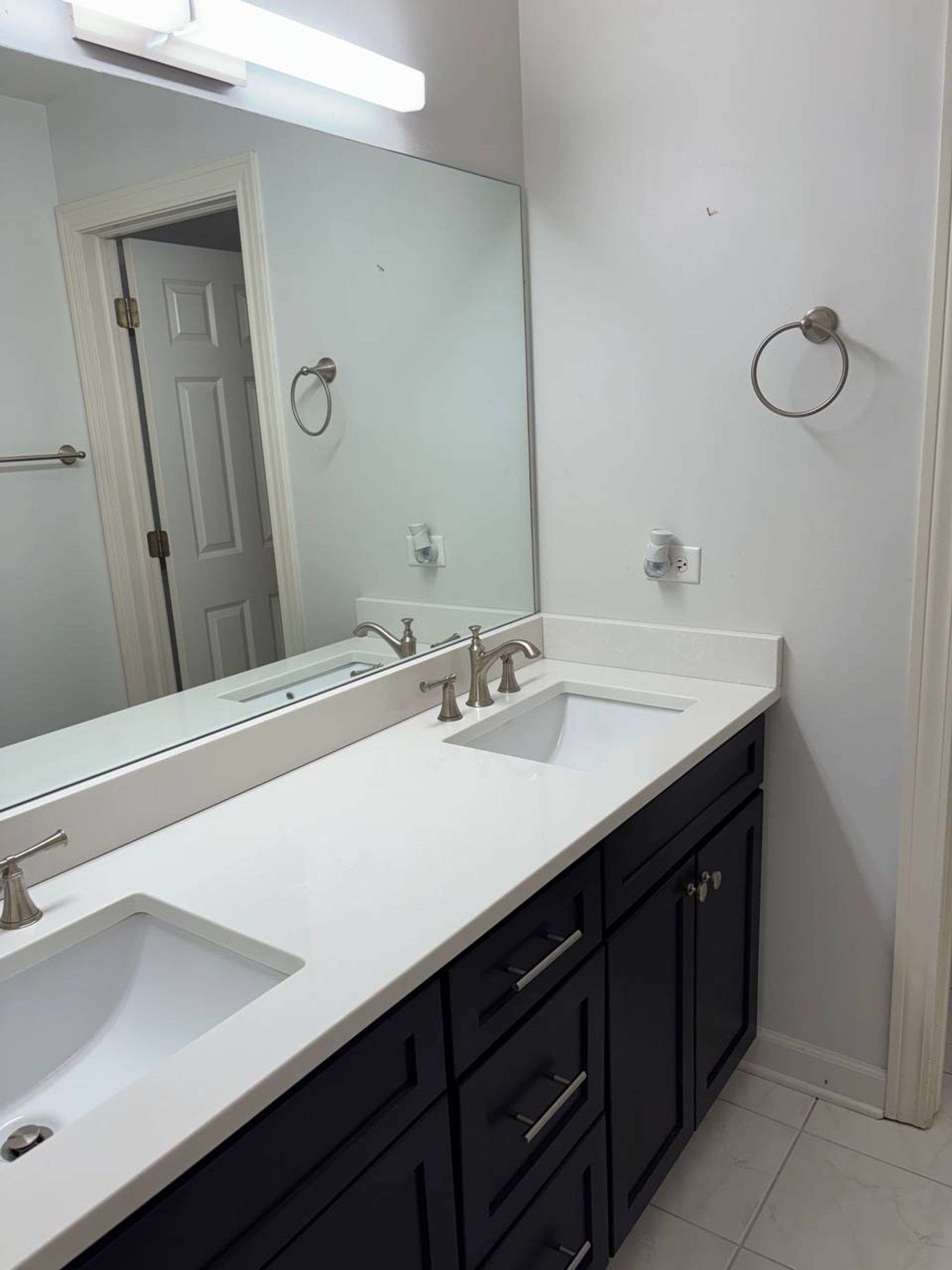 Double sink vanity with white quartz top and dark gray cabinets