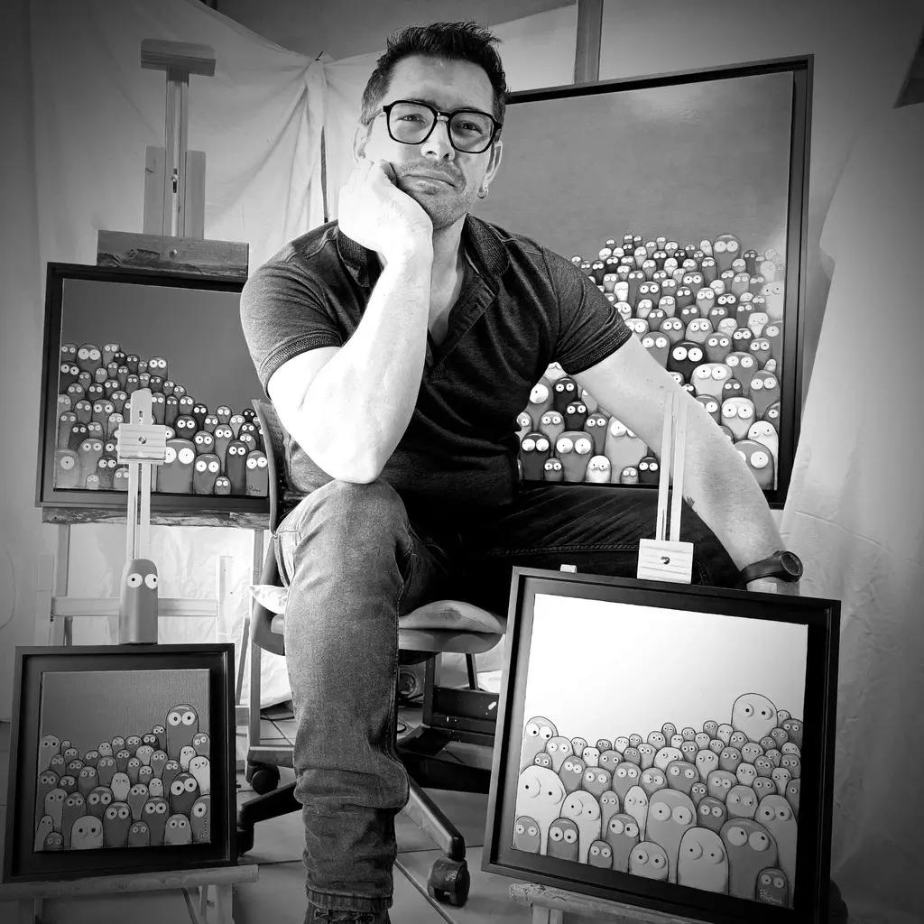 Portrait en noir et blanc de Rémy Tuybens avec plusieurs de ses œuvres