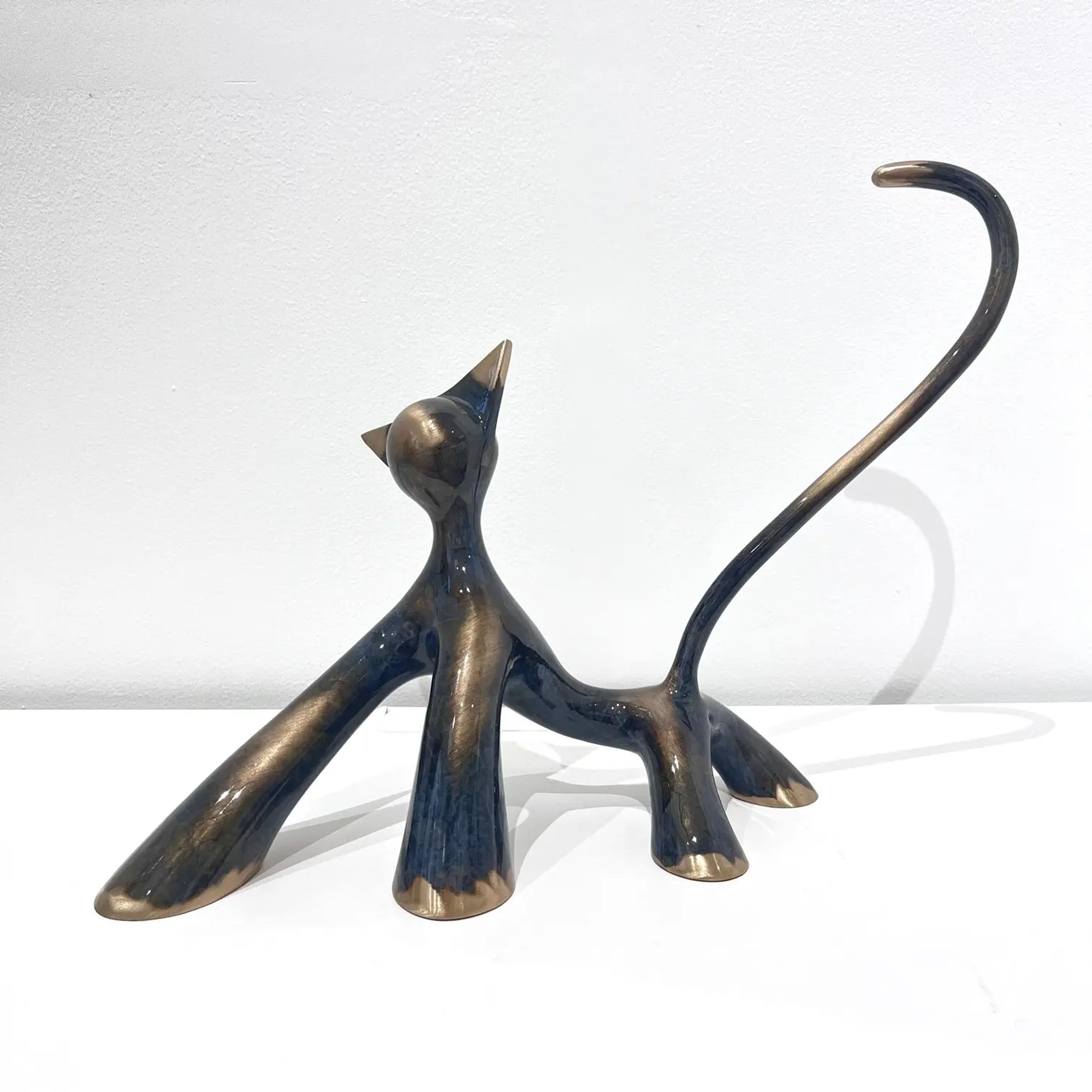 Sculpture féline noire et grise brossée meulée, queue haute, contrastes mats et brillants, posture assurée.