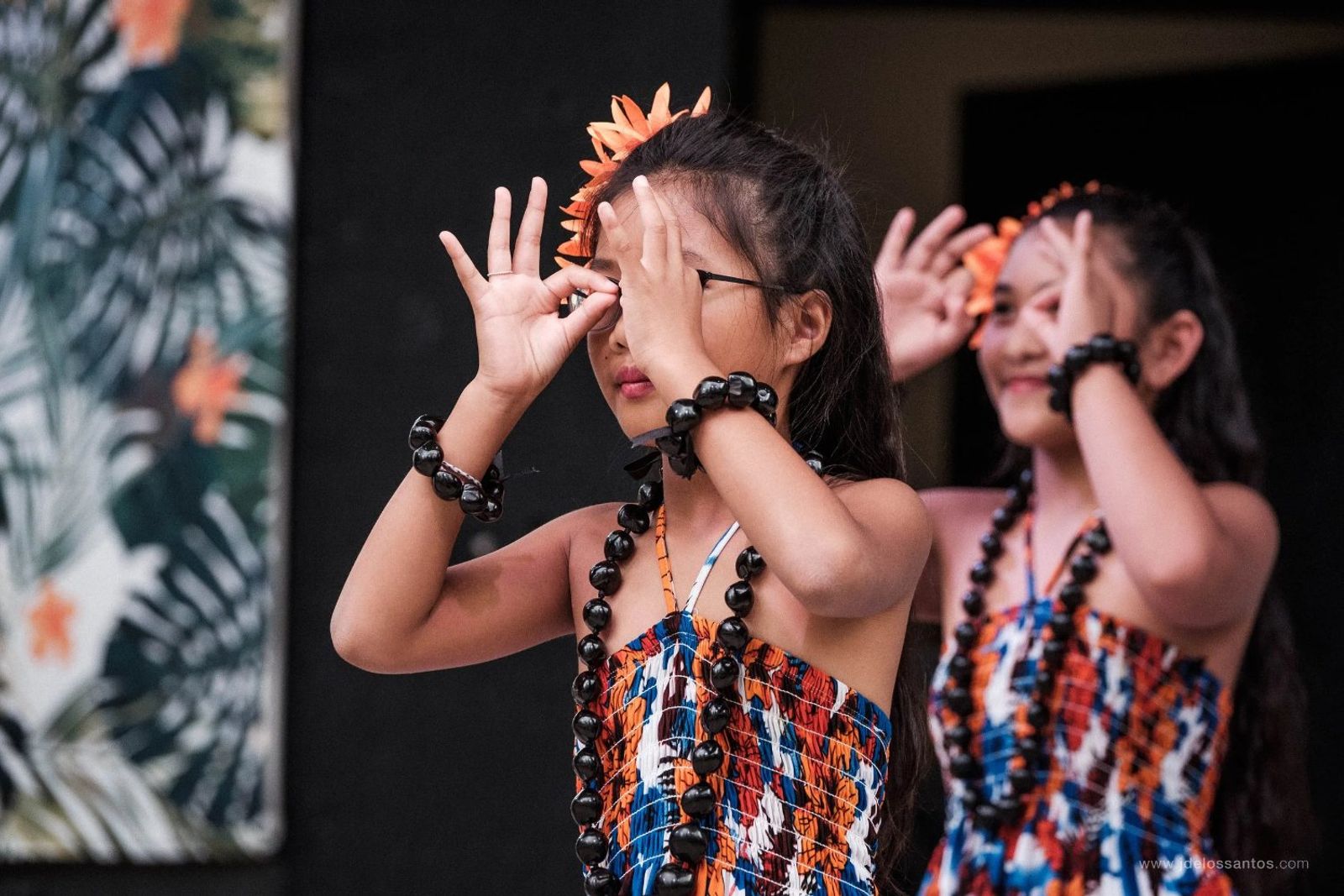 Young hālau dancers performing a traditional hands-over-eyes gesture