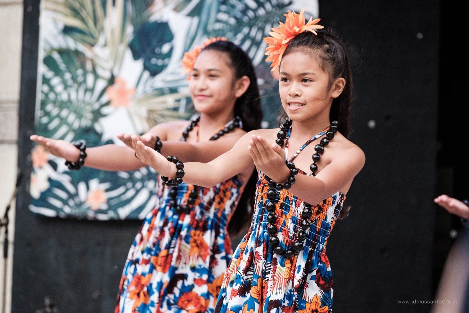 Two young hālau dancers extending their arms in unison