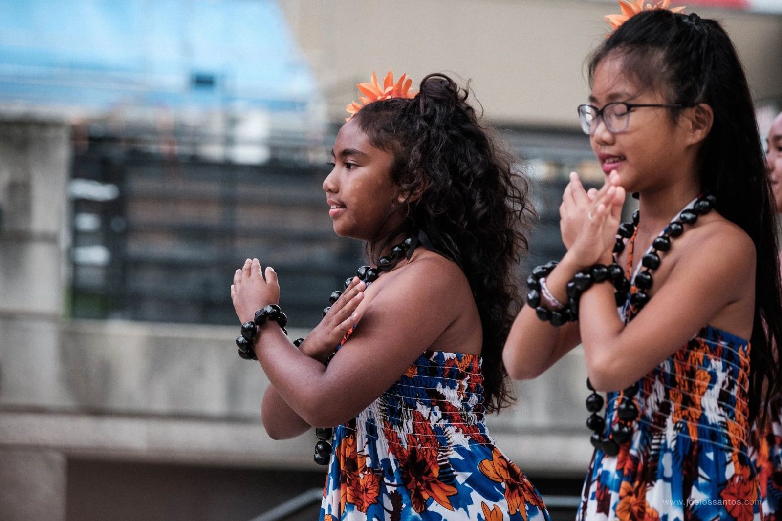 Two young hālau dancers in a prayer-hands gesture