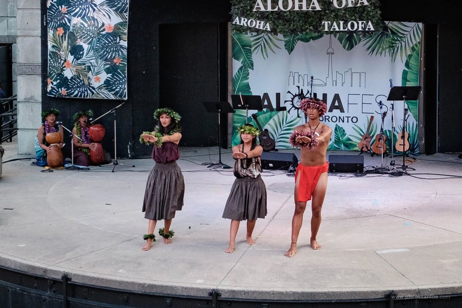 Three hālau dancers in hula kahiko attire on the AlohaFest Toronto stage