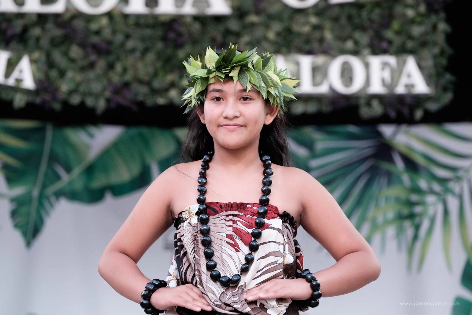 Portrait of a young hālau dancer in grey pāʻū with a green maile lei crown