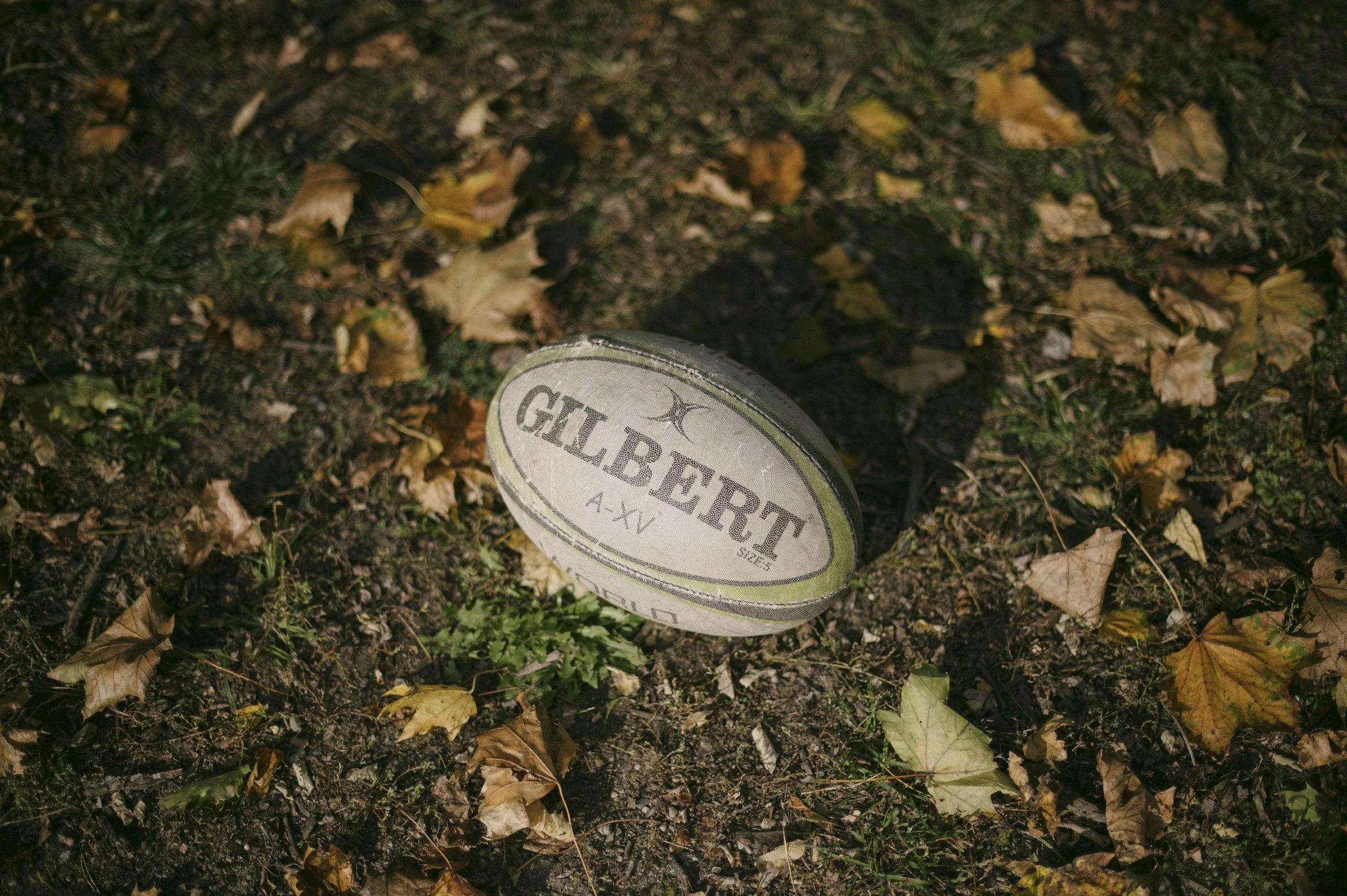A rugby ball on the ground among fallen leaves