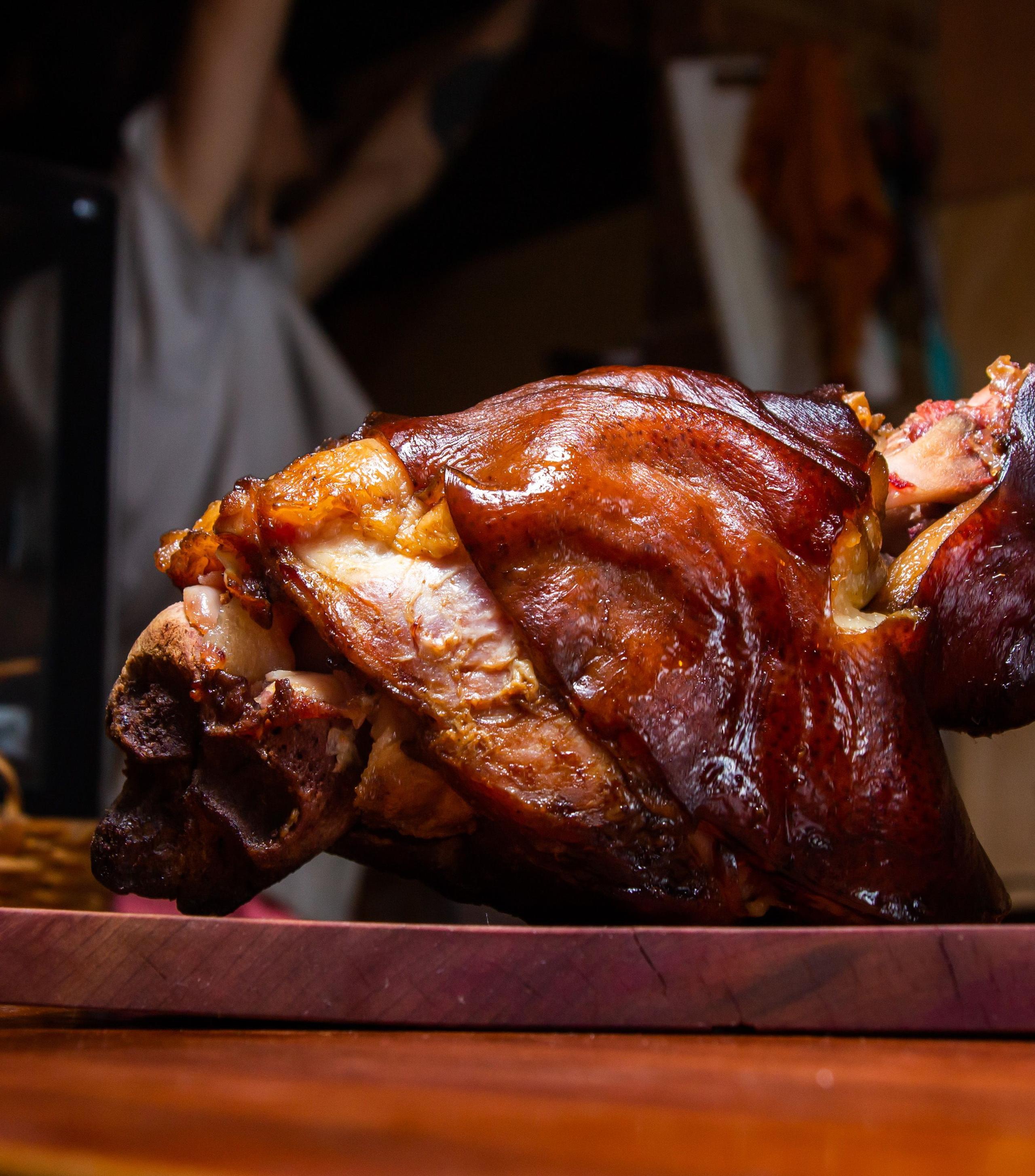 Illustrative stock photograph of a crisp-skinned pork knuckle on a board; restaurant presentation differs