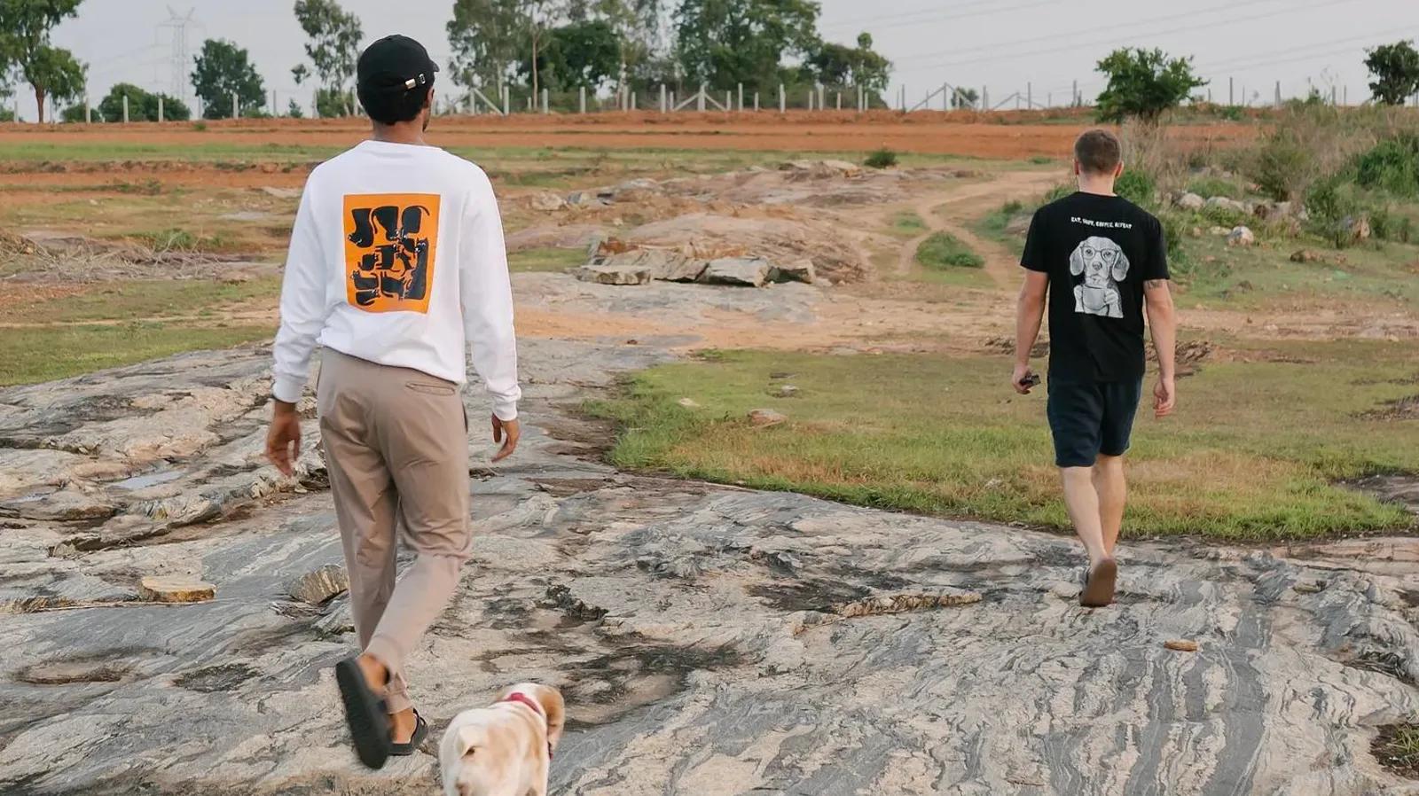 Two Dognosis team members walking across a rocky field with a dog