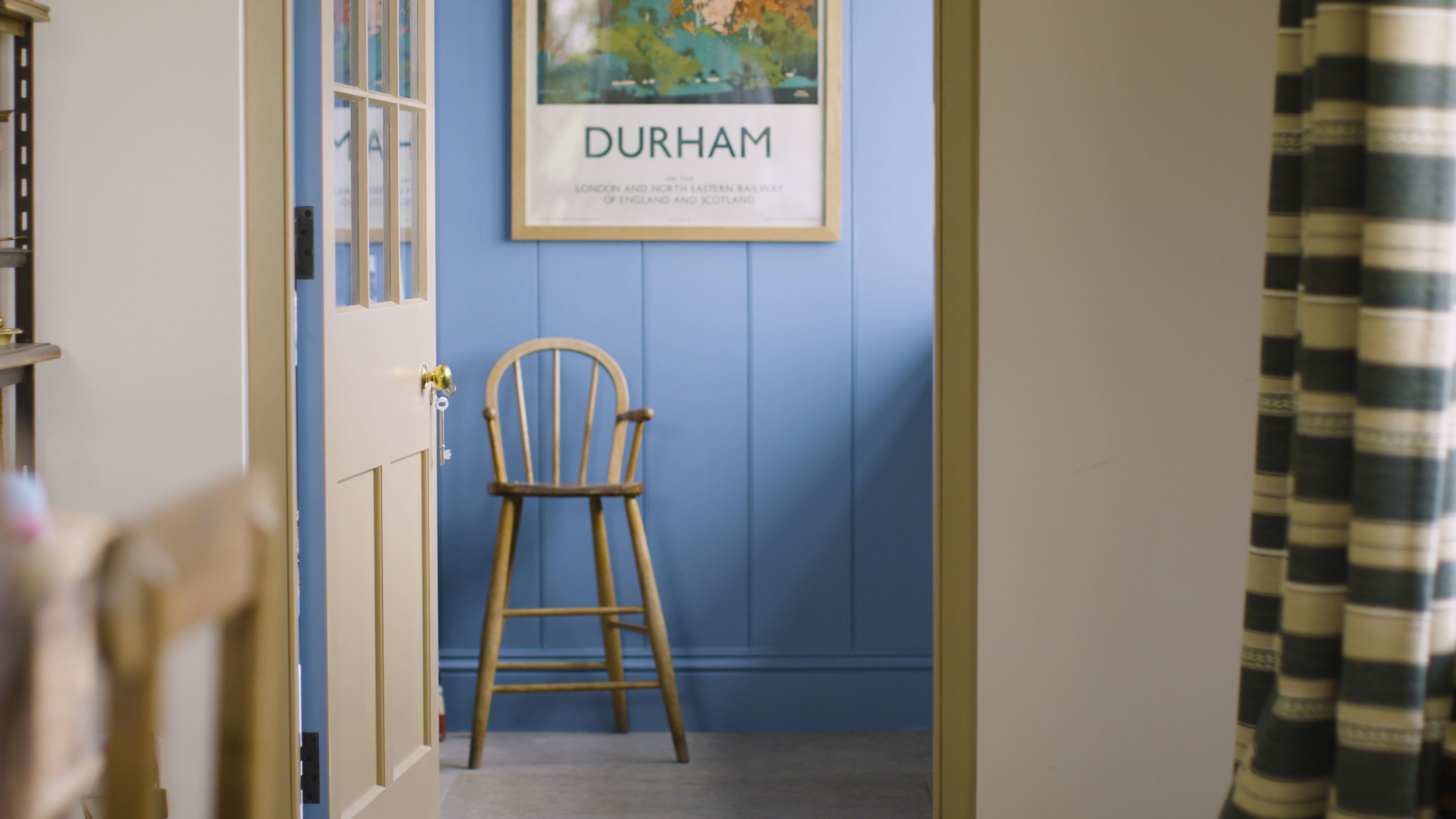 A view of Rita Konig's kitchen doorway opening up into a lardar room. The first room is painted a soft yellow and the second room is painted a mid-toned blue.