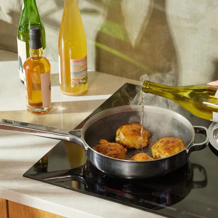 A chrome finish pan from Our Place sits on a countertop.