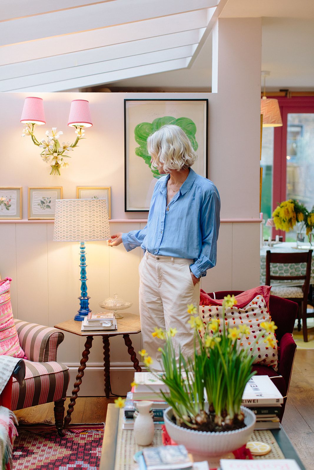 Rosi de Ruig stands in her living room. She touches the shade of a lamp on a corner table.