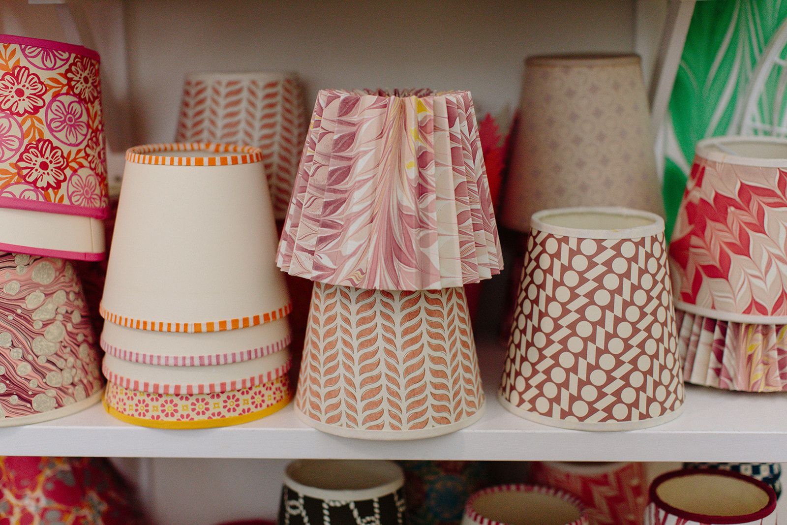 A book shelf stacked with colourful paper lampshades