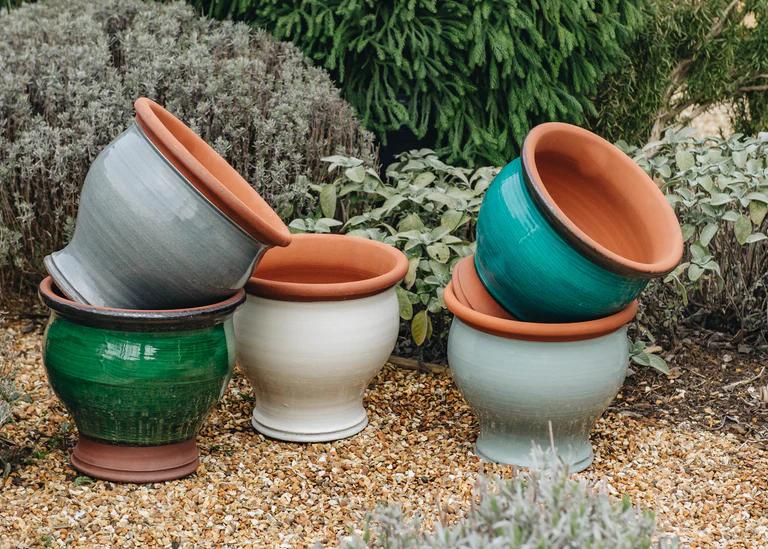 Five medium-bellied plant pots in various colours, green, teal, white and grey. The pots are terracotta with colourful glazes. 