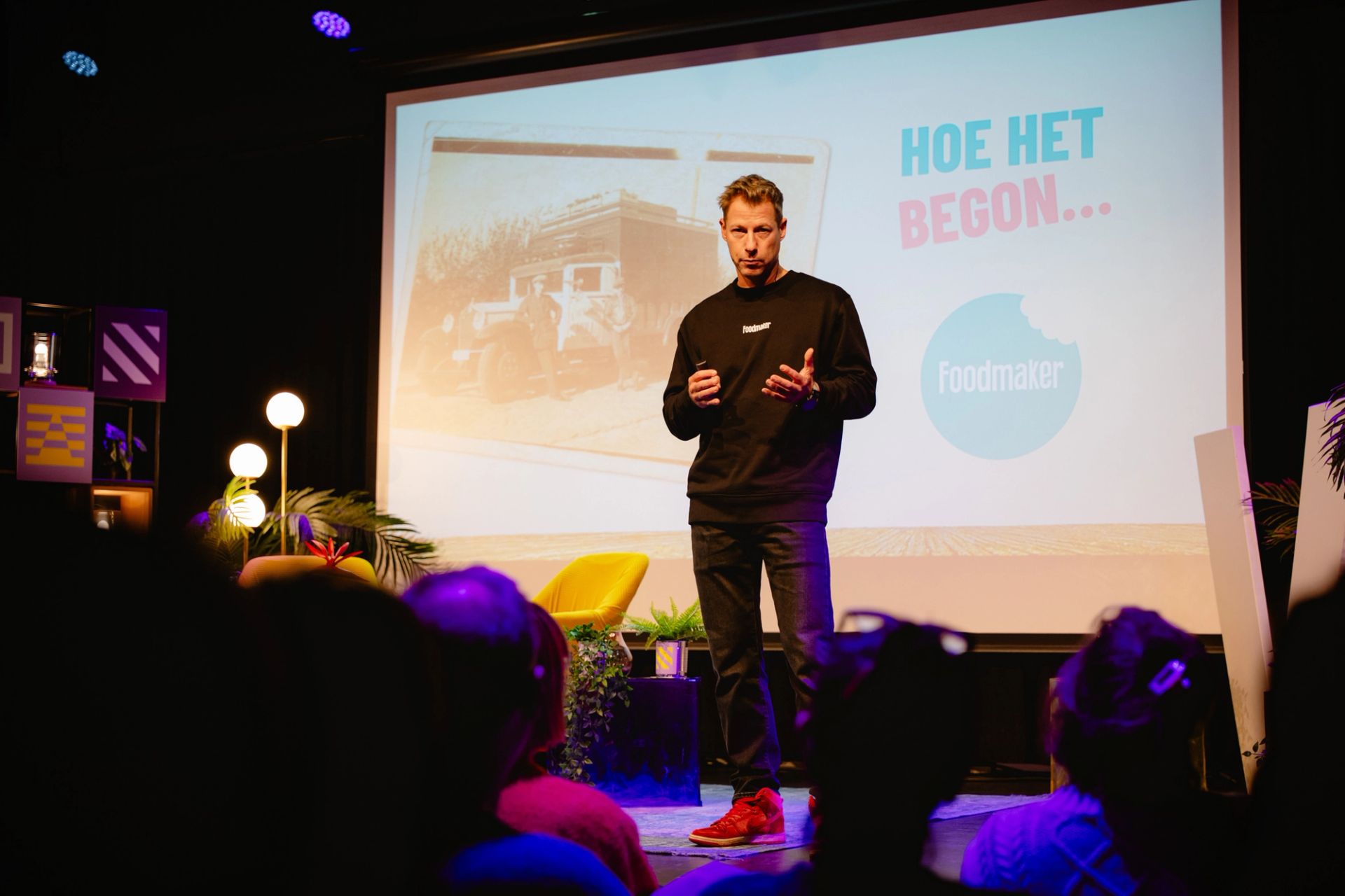 Lieven Vanlommel, CEO of Foodmaker presents on stage in front of a slide reading "Hoe het begon."