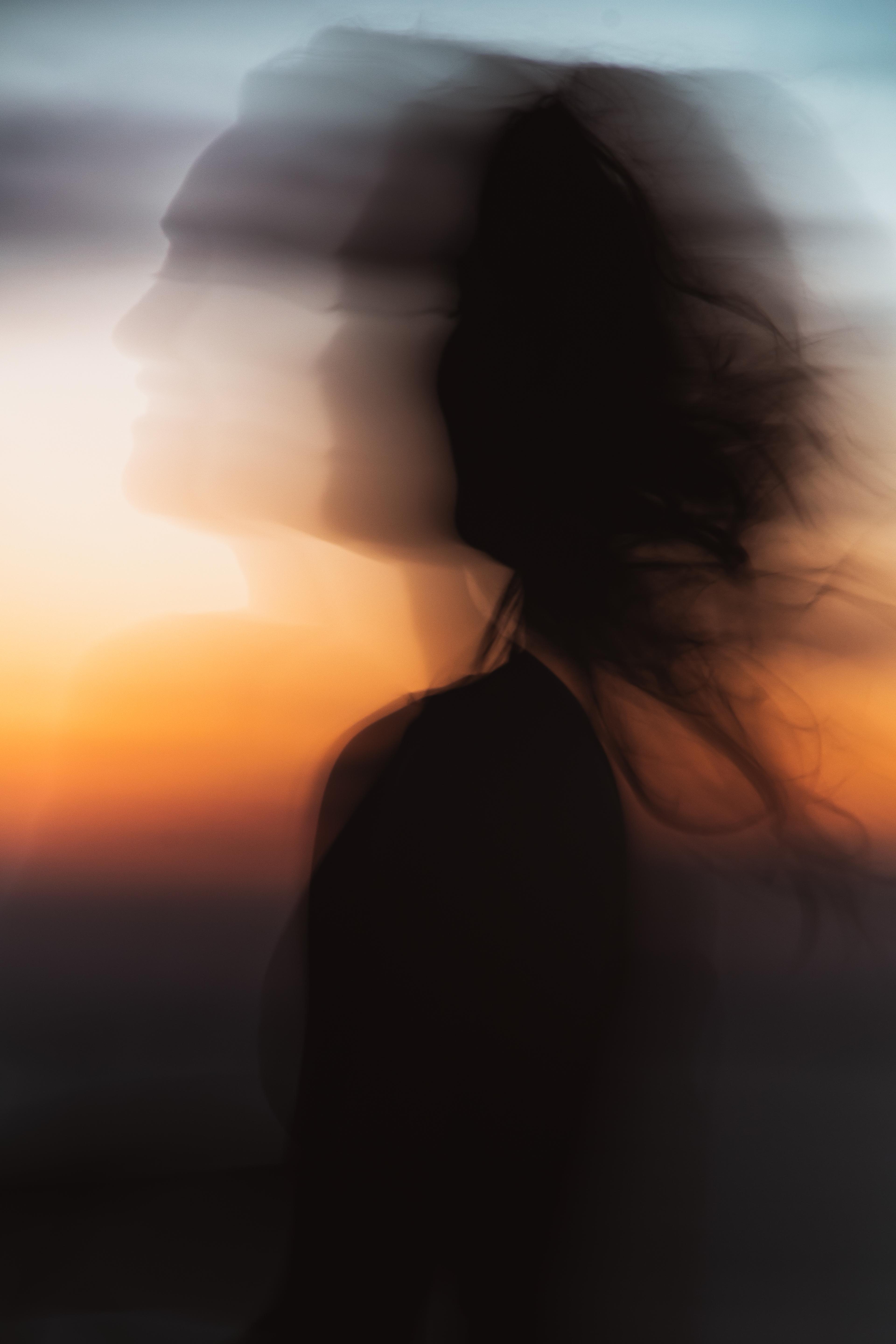 A vague silhouette against the warm colours of a setting sun in which you can see a dancing lady 