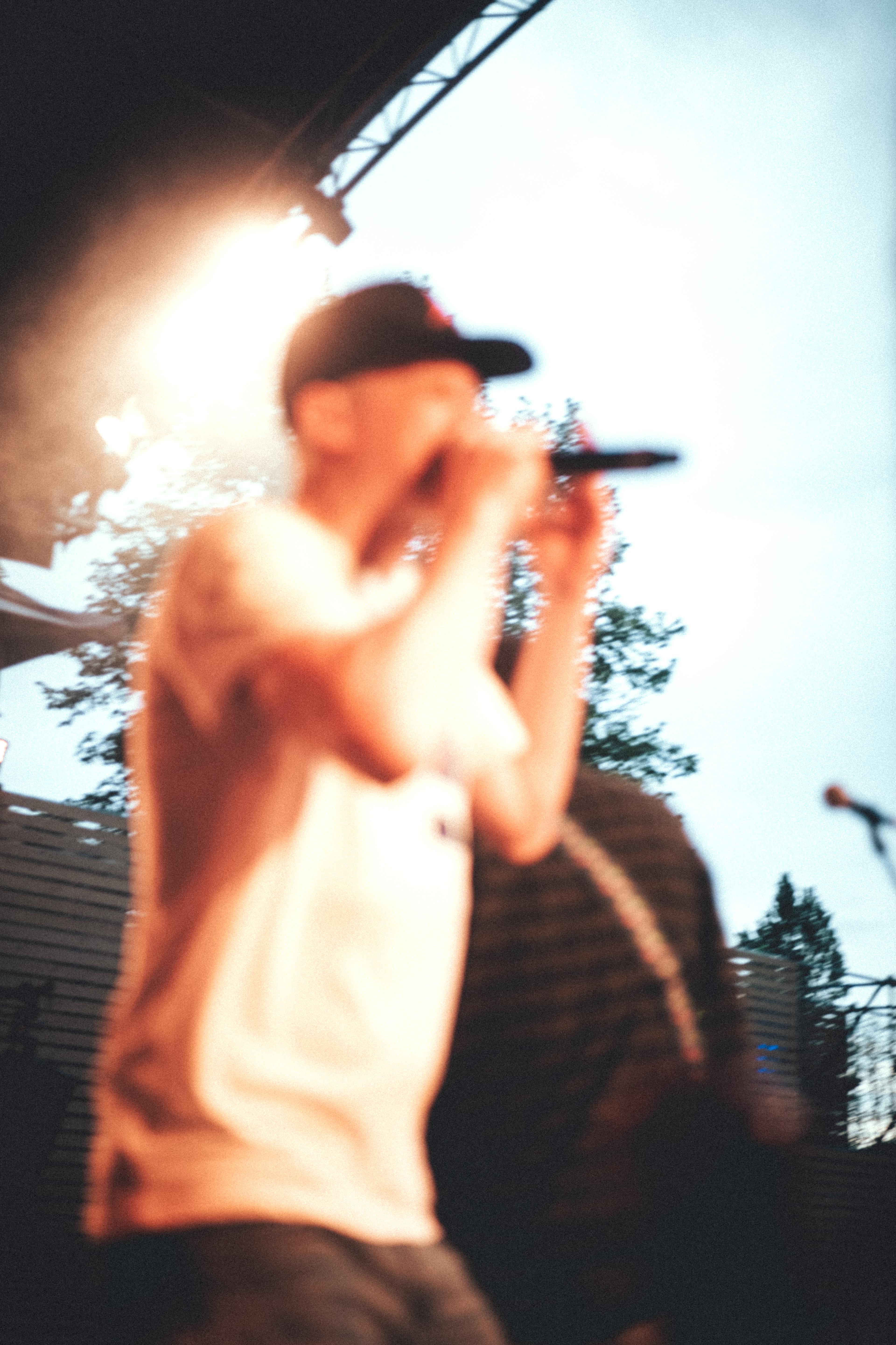 The out of focus silhouette of the lead singer and rapper in an orange spotlight with the blue sky in the background