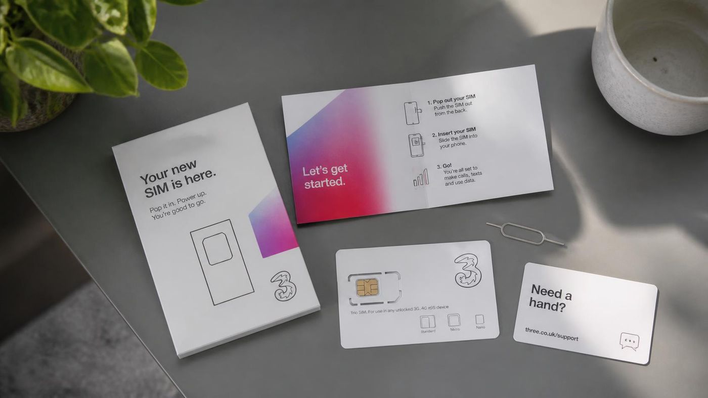 UK SIM card packaging and welcome leaflet for Three on a table, with a SIM ejector tool and a Need a hand support card.