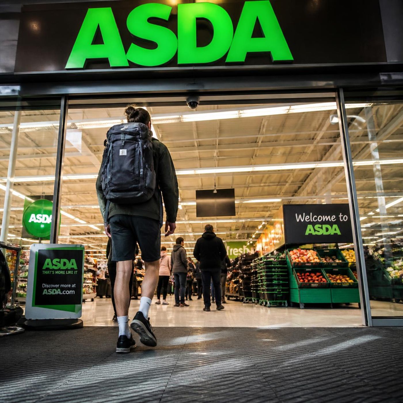 ASDA supermarket entrance with a shopper walking through the automatic doors