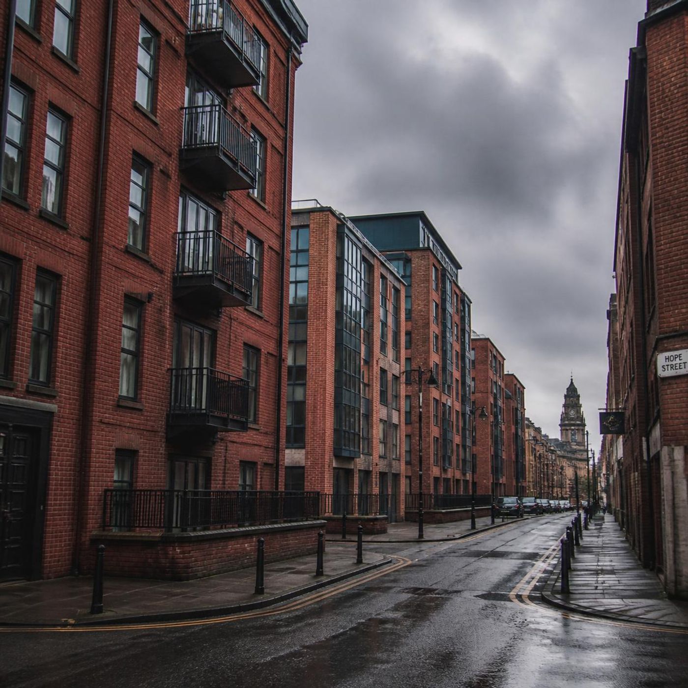 Red brick apartment buildings with iron balconies on a wet UK city street