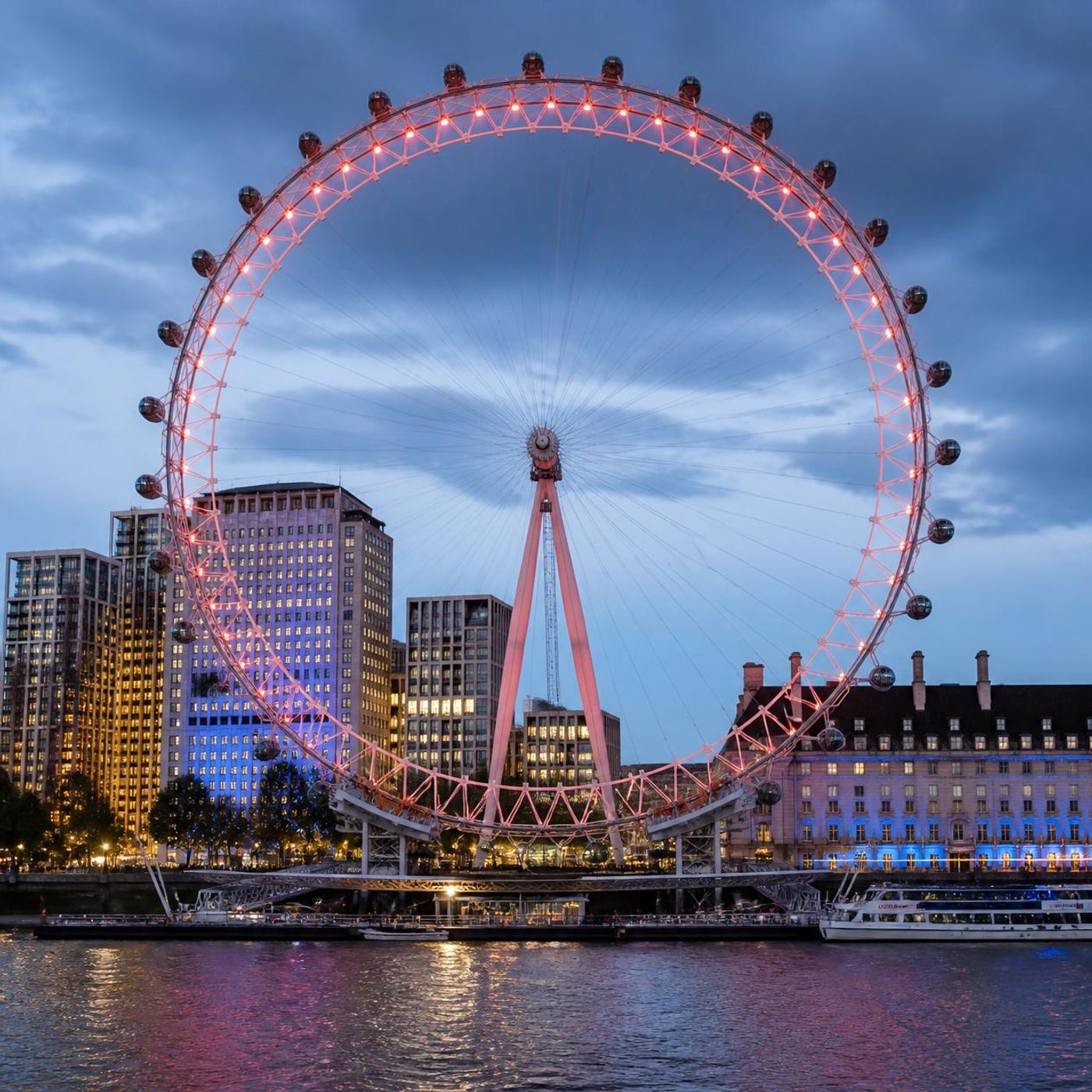 London Eye illuminated at dusk with the Thames and South Bank buildings