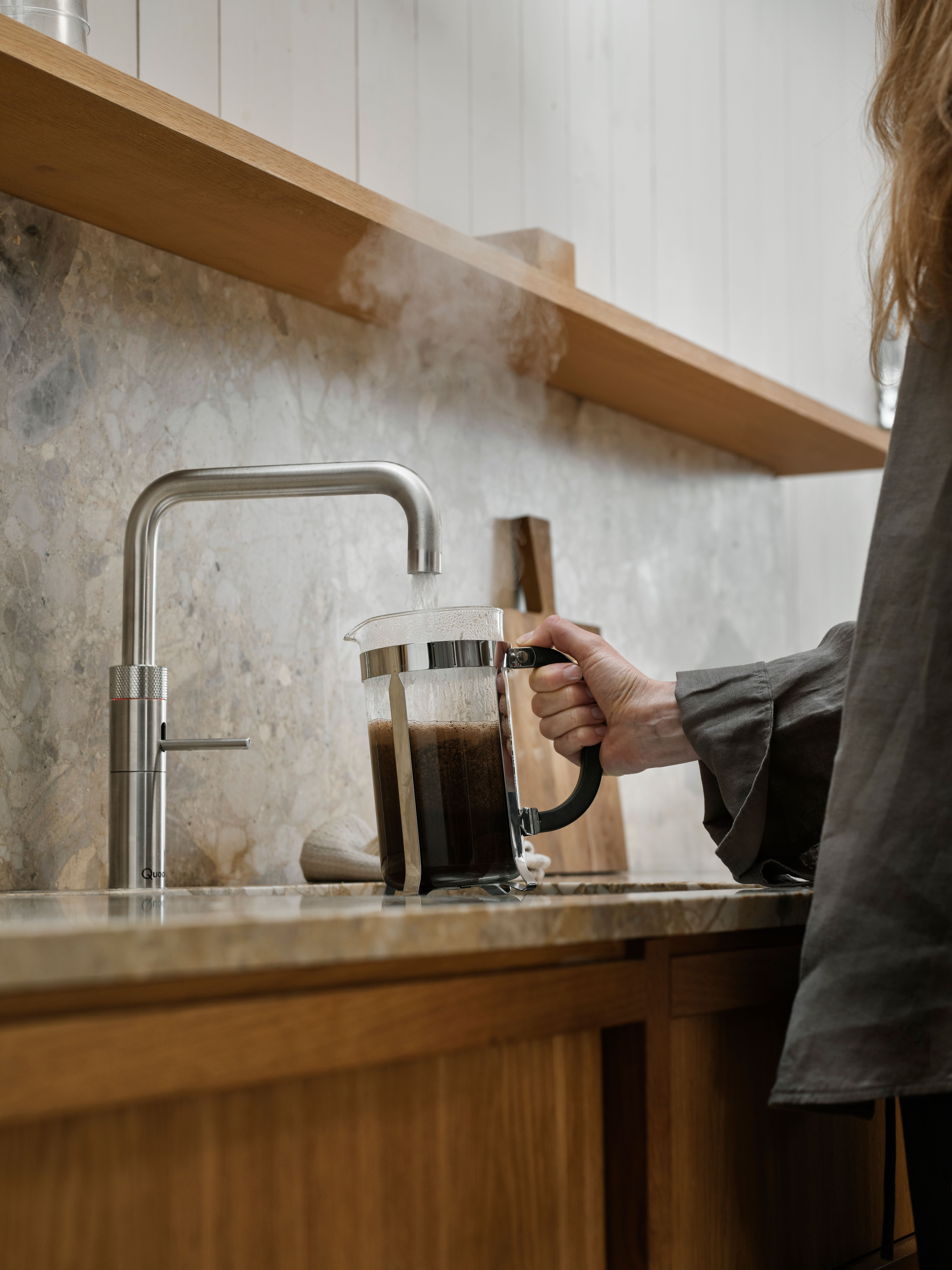 Kvinne fyller kokende vann i stempelkanne med kaffe