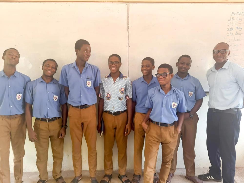 Secondary school students in blue uniforms standing with two adults during the Global Learning for Africa research project.