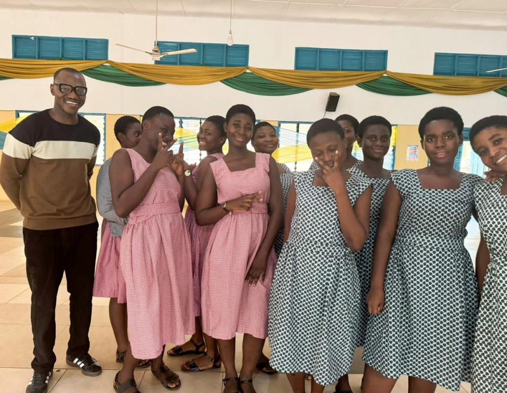Secondary school students in patterned uniforms standing with an adult during the Global Learning for Africa research project.