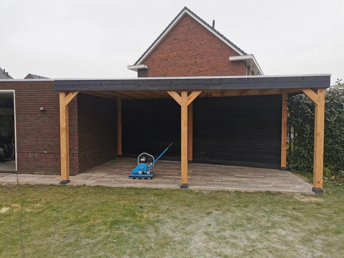 Douglas overkapping met zwarte achterwand aan een bakstenen woning