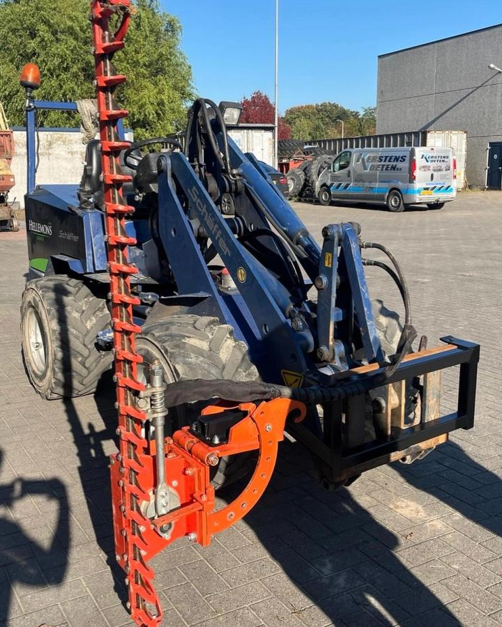 De eigen shovel van Hellemons Groen met een snoeizaag ervoor, klaar om machinaal te snoeien