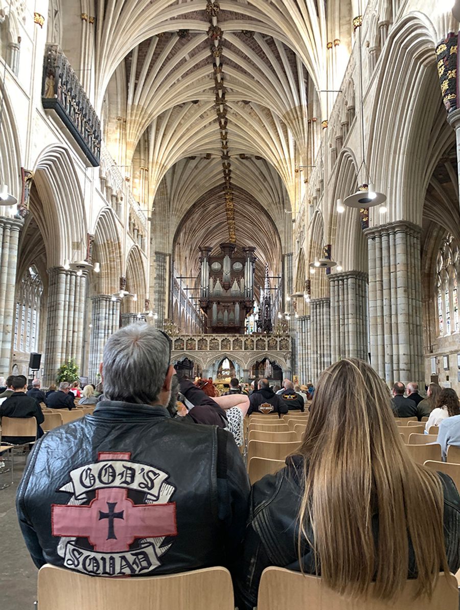 Service inside the cathedral; in the foreground, a biker wearing a 'God's Squad' jacket