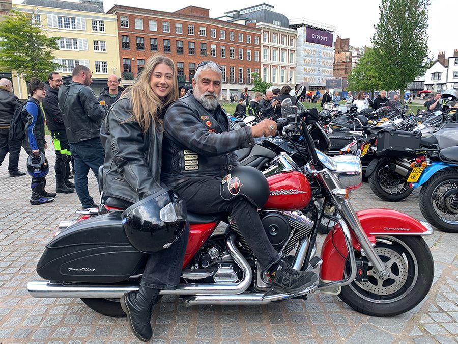Man and woman posing on a big red Harley Davidson bike