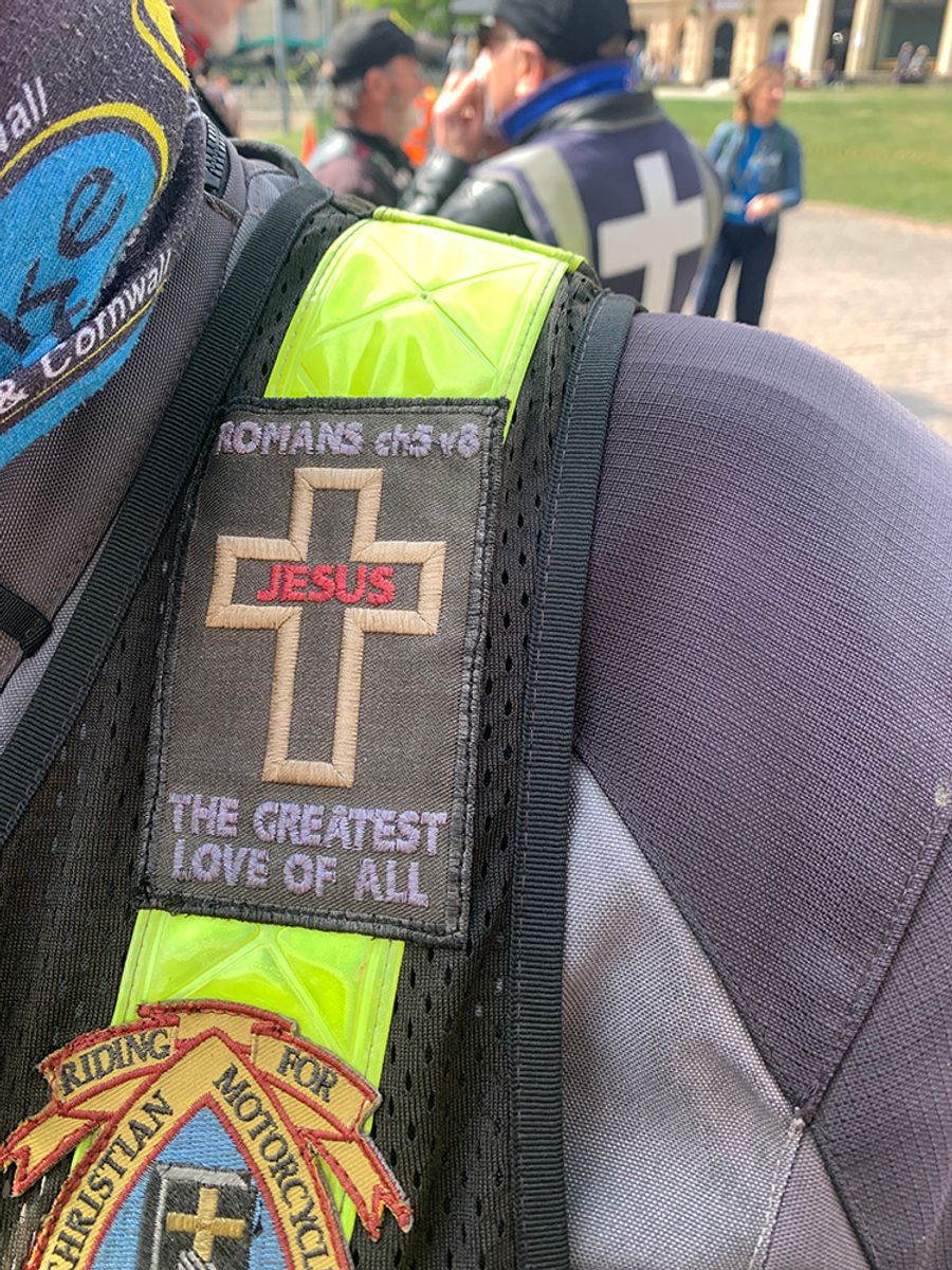 Biker patches reading 'Romans ch5 v8: Jesus, the Greatest Love of All' and 'Riding for Christians Motorcyclists Association''