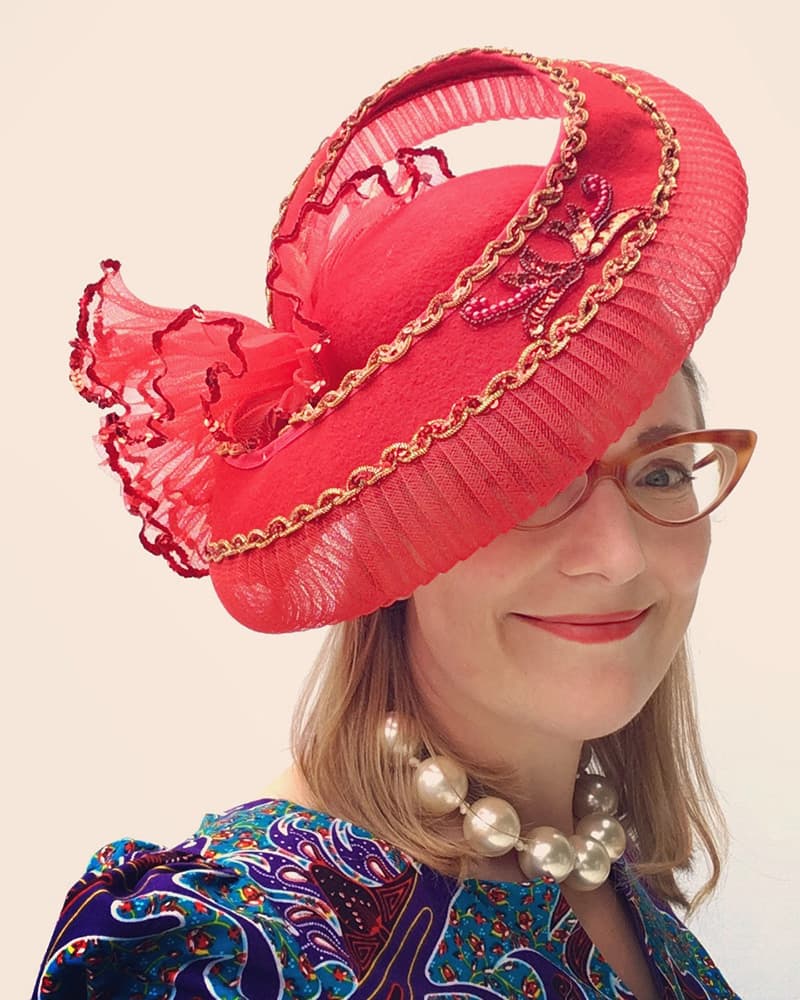 Sarah McIntyre wearing a hat, smiling beatifically