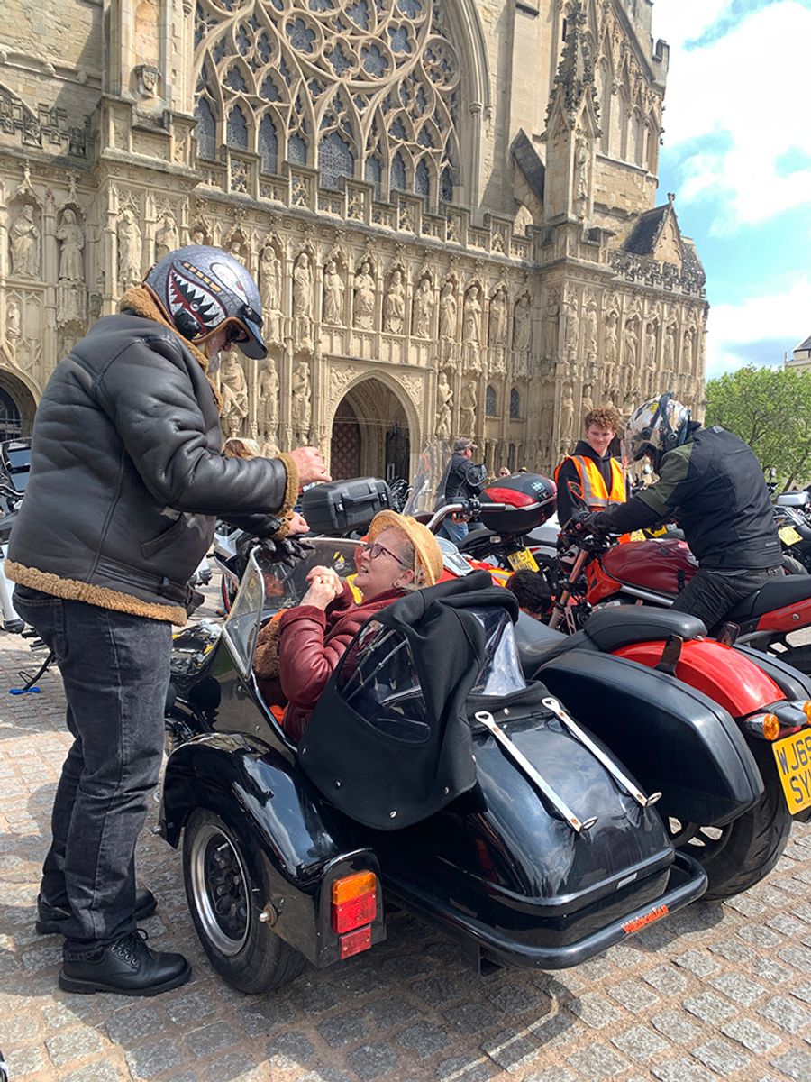 Biker couple in front of Exeter cathedral: the man has dismounted and the lady is still seated in the sidecar