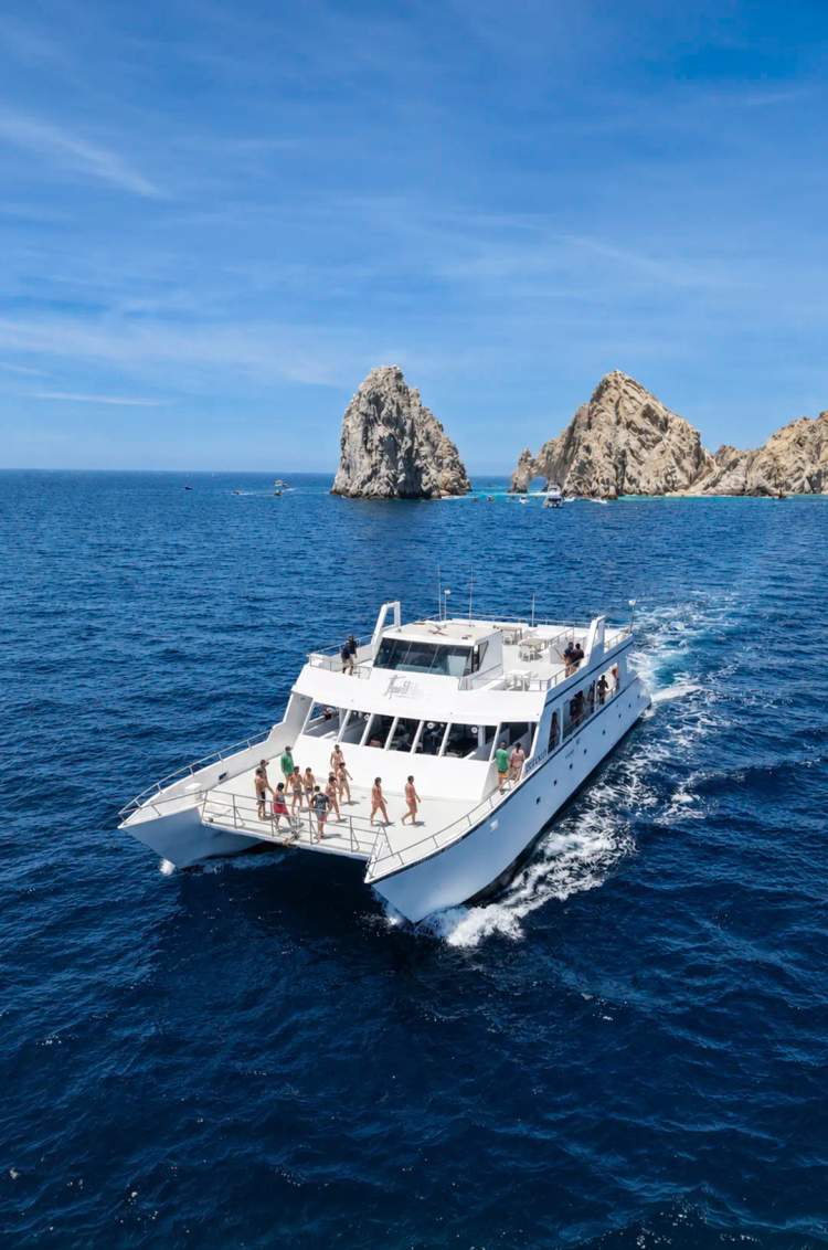 Catamarán Oceanus de snorkel en Cabo San Lucas navegando junto al Arco con vistas al mar y ambiente social
