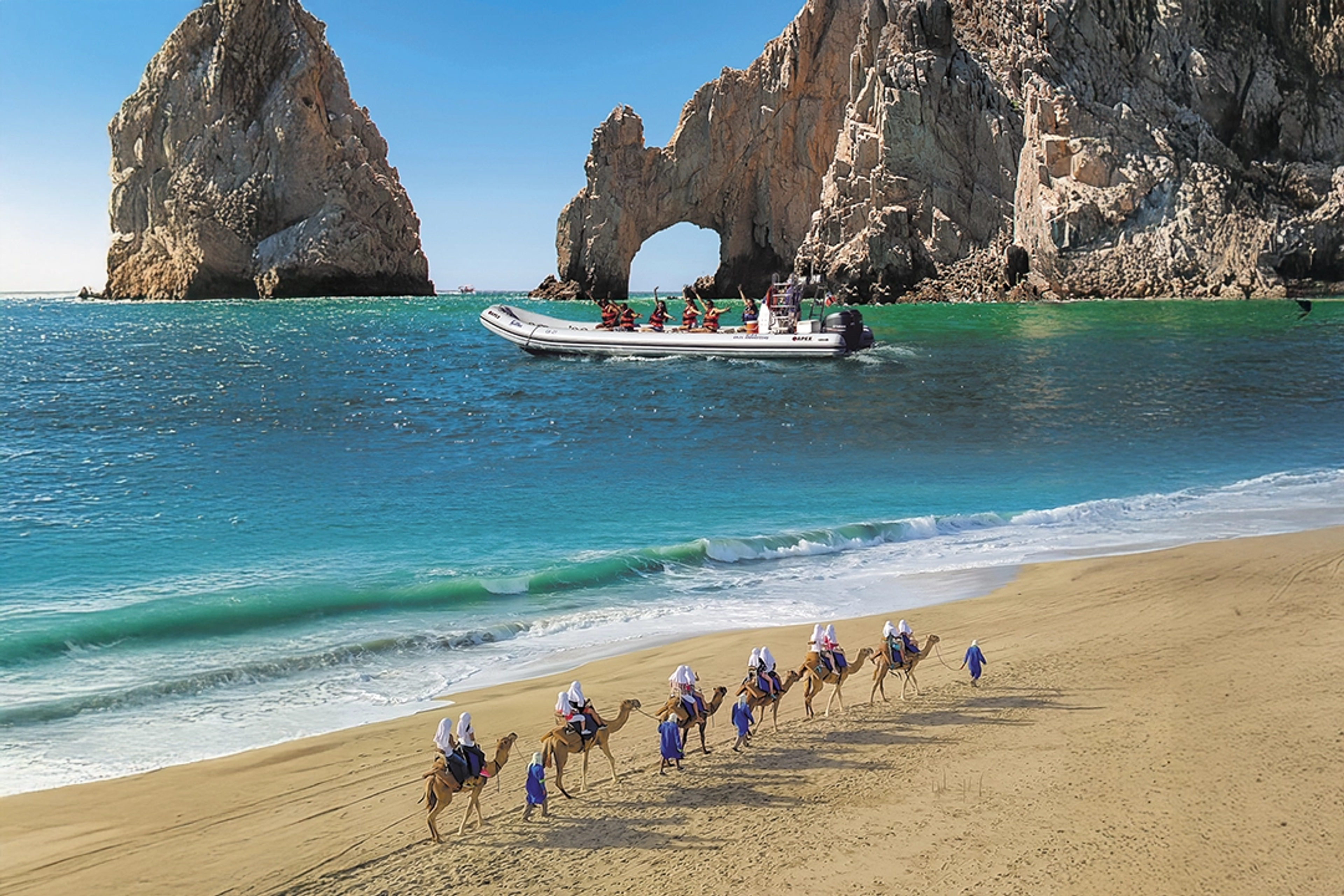 Una caravana de camellos en una playa de arena con un bote cruzando aguas turquesas cerca del famoso Arco de Cabo San Lucas.
