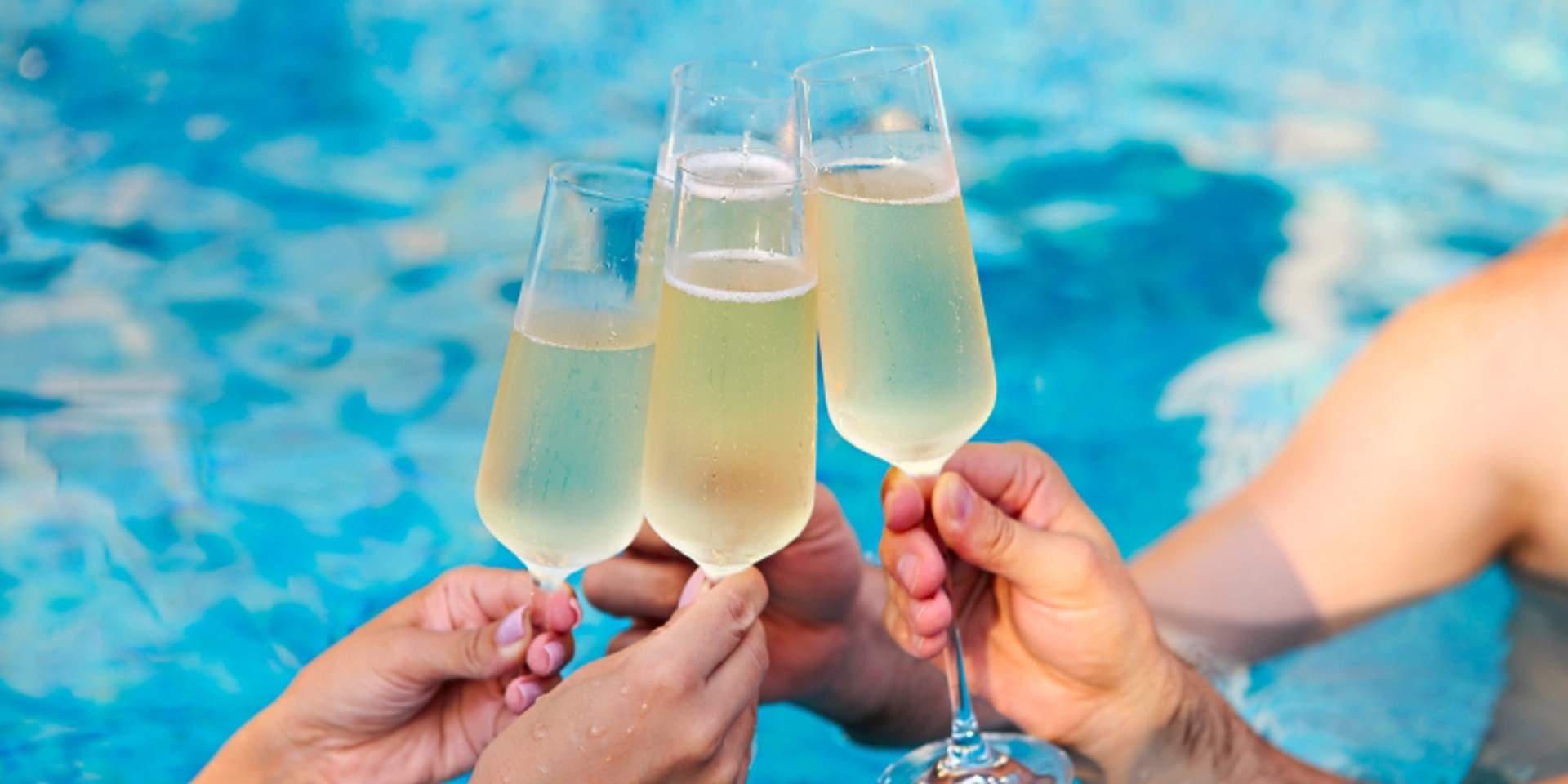 Friends toasting champagne glasses in the pool at Tierra Sagrada Beach Club in Cabo San Luca