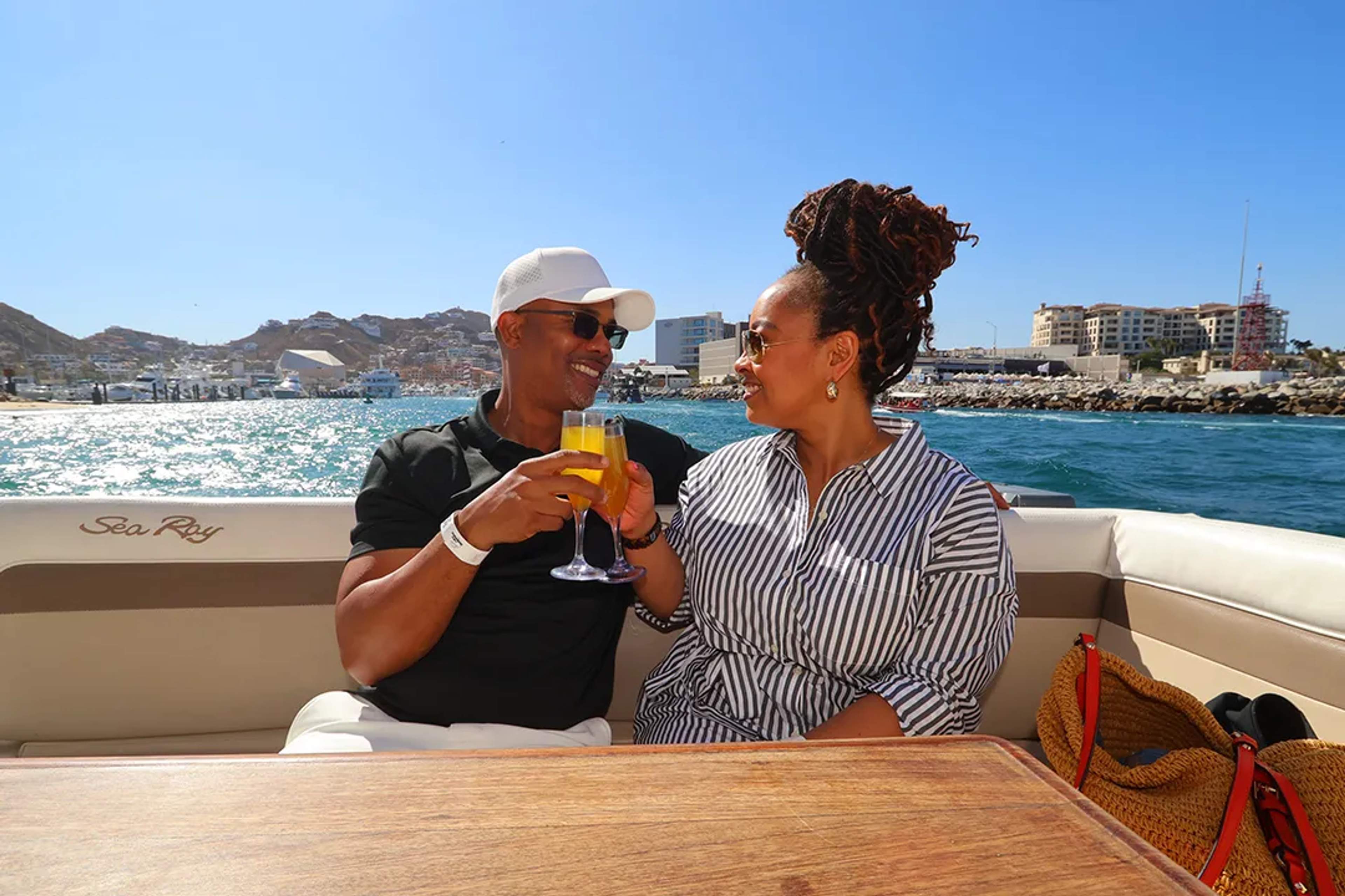 Couple toasting with drinks aboard a luxury yacht in Los Cabos, enjoying ocean views and a relaxed coastal atmosphere