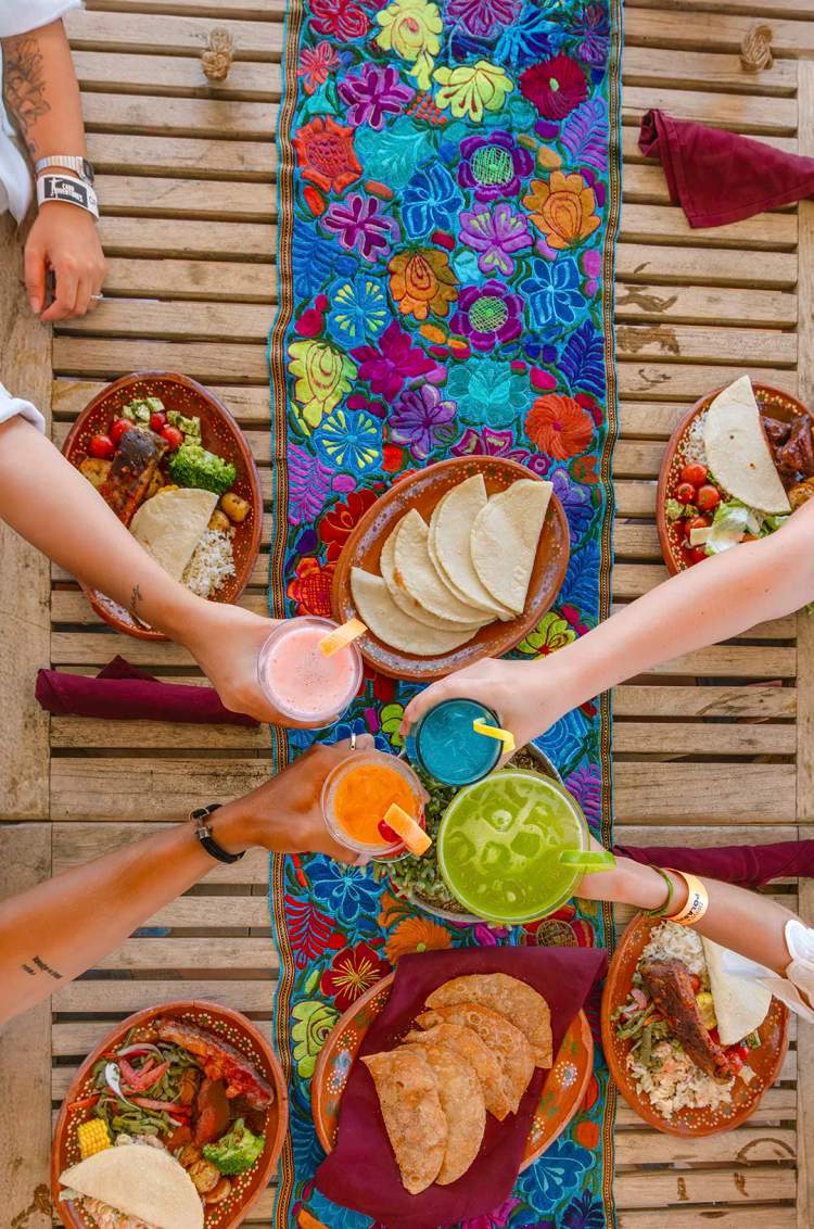4 persons toasting over a colourful table 