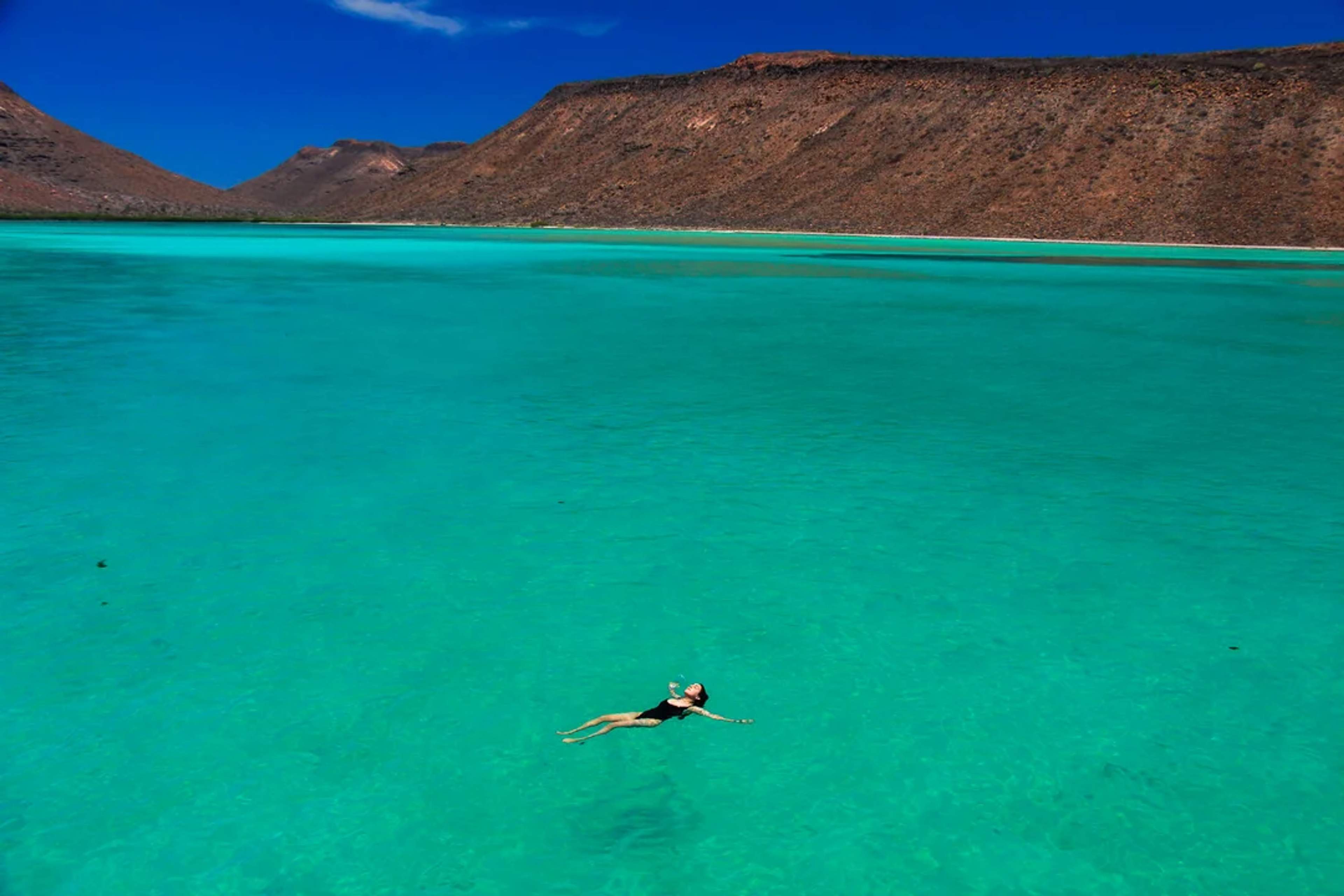 Woman floats peacefully in Balandra’s calm, crystal-clear turquoise waters.