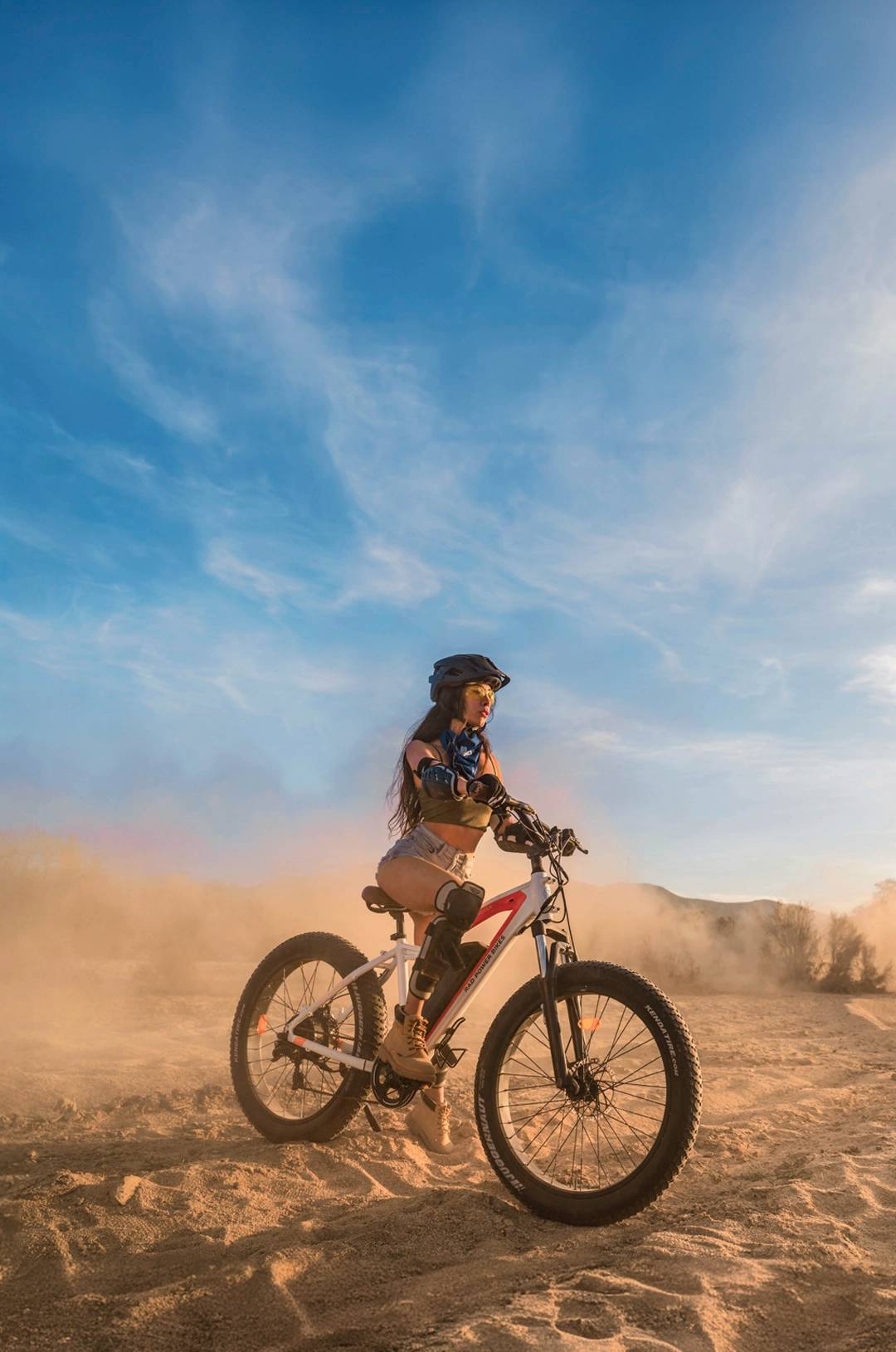 Electric bike tour in Cabo, woman riding through sandy terrain with a dramatic sky backdrop.
