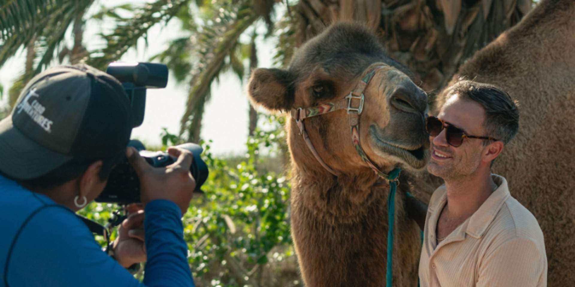 Tourist posing with camel while photographer captures the moment at Tierra Sagrada in Cabo