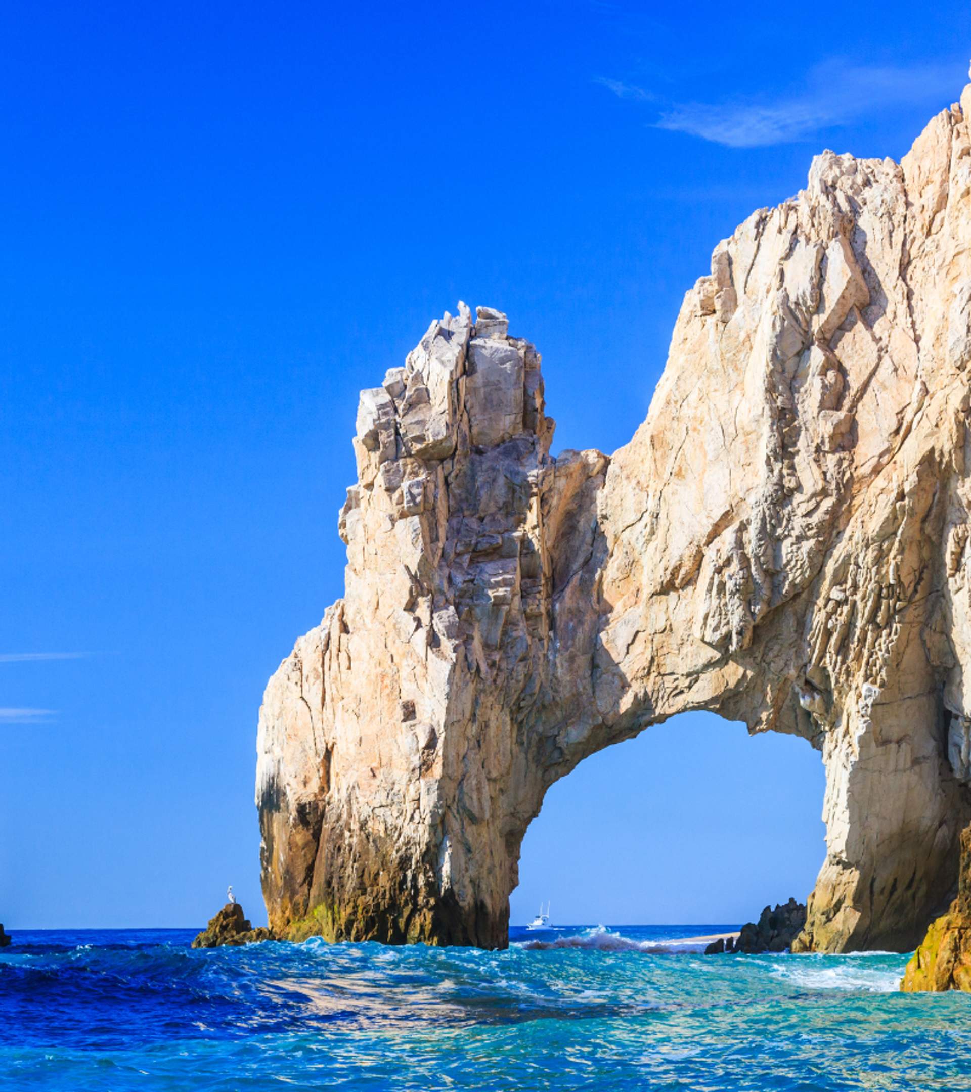 The iconic Arch of Cabo San Lucas, a natural rock formation with a blue sky and ocean backdrop, a popular sightseeing spot in Cabo.